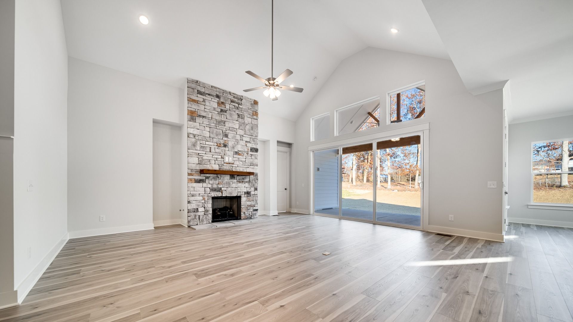 Spacious gathering room with ceiling fan, fireplace, and hard surface flooring