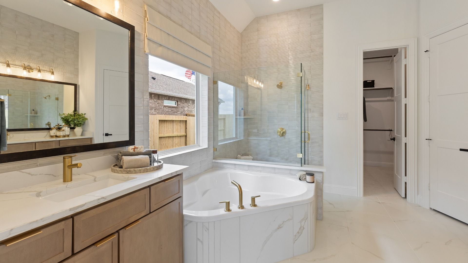 This spa-inspired primary bath features stunning marble tile details and warm-toned cabinetry.