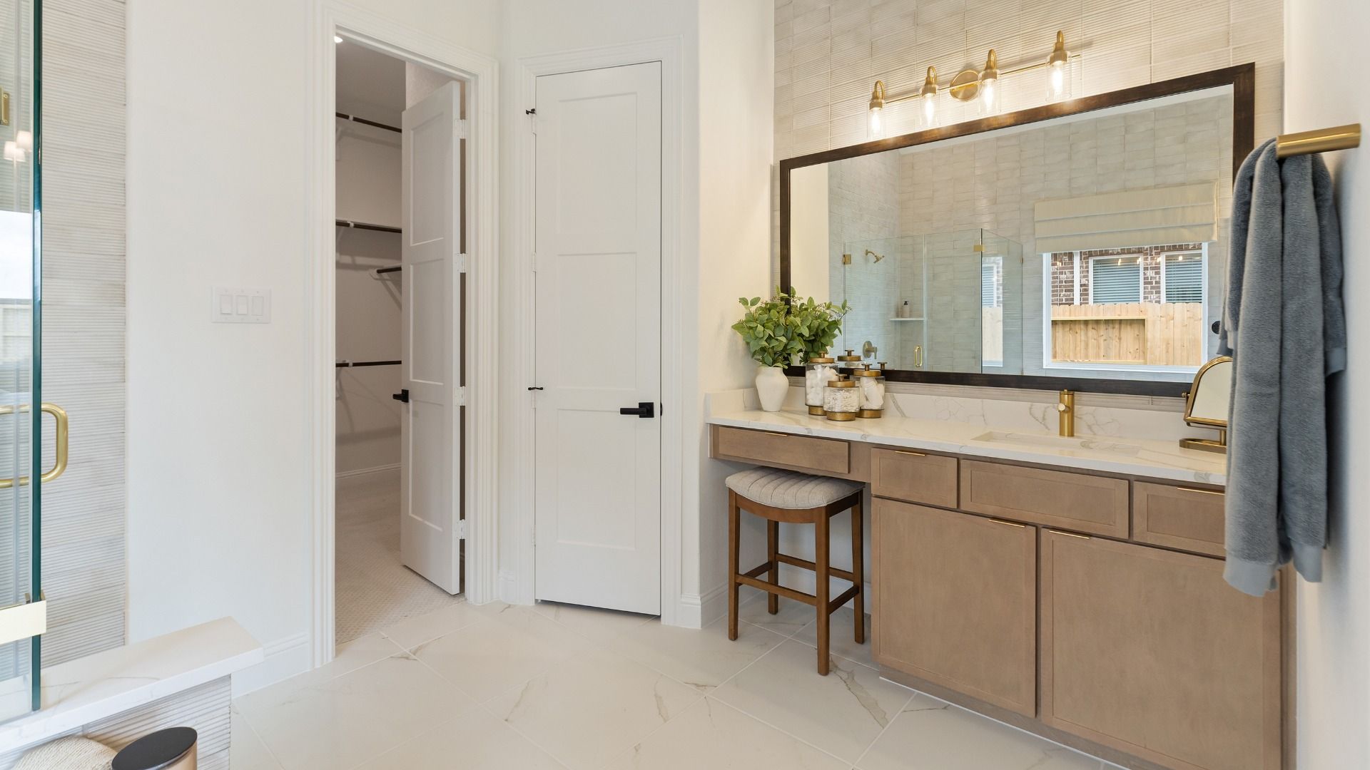 Convenient vanity space in the chic primary bath with designated seating and ample lighting.