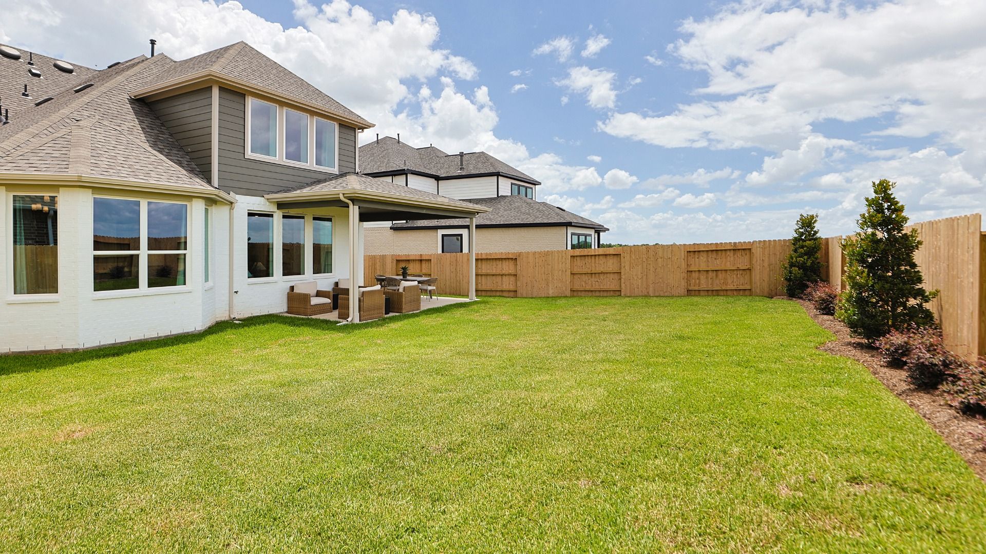 Spacious backyard with lush, green grass and tasteful landscaping in Grand Magnolia.