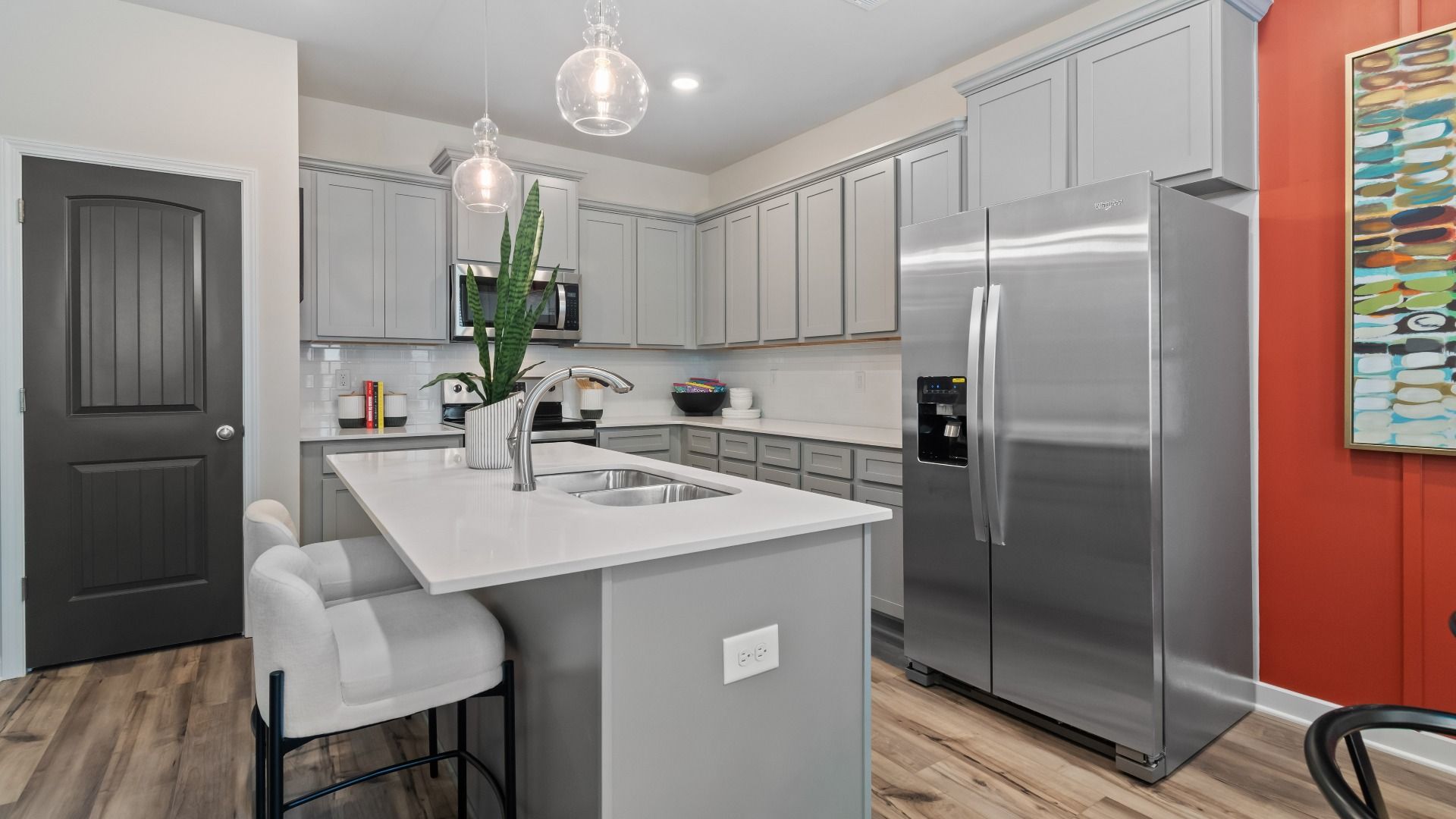 Kitchen with grey cabinetry, quartz countertops, and tile backsplash