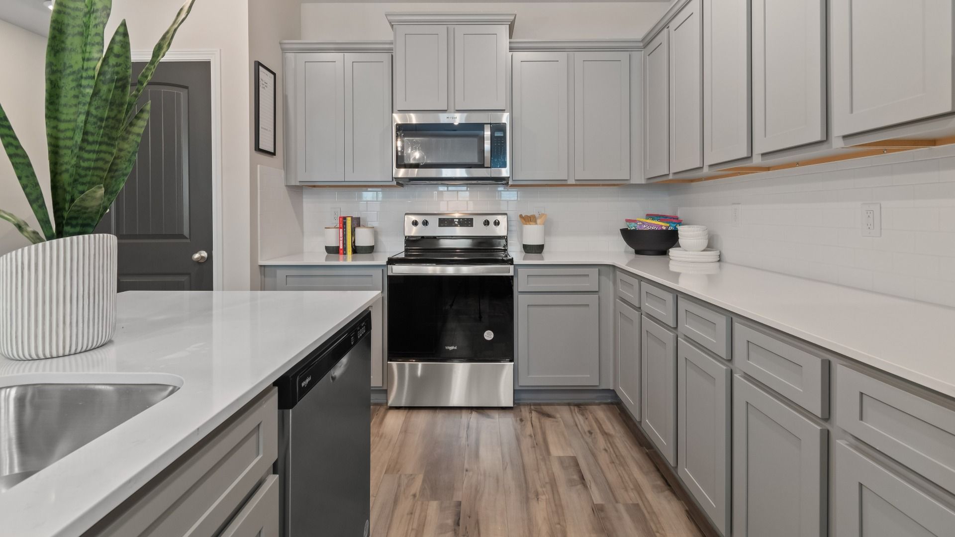 Kitchen with grey cabinetry, quartz countertops, and tile backsplash