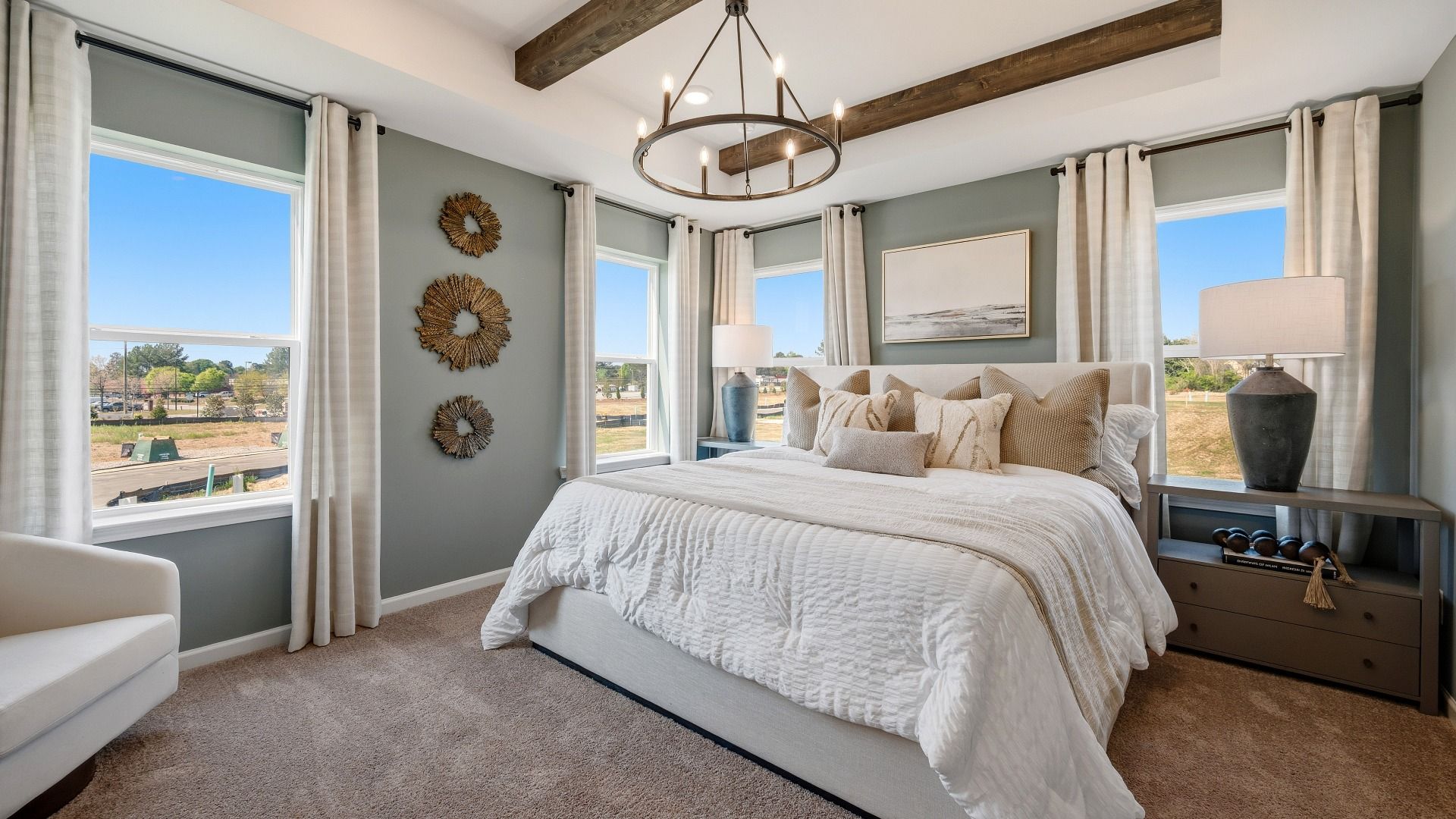 Primary bedroom with tray ceiling, accent ceiling, carpet, and windows