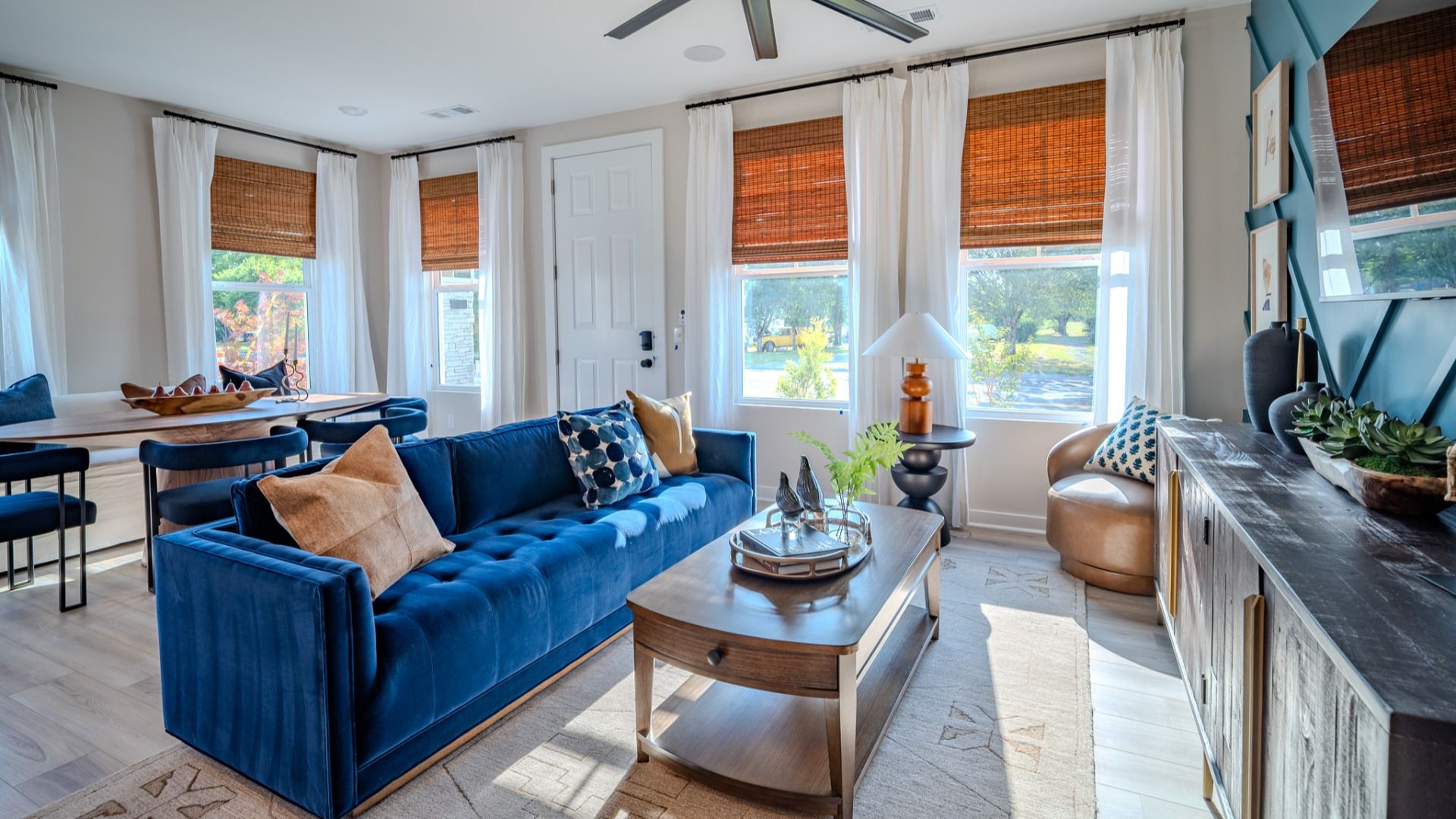 Living area with ceiling fan, accent wall, and access to dining area