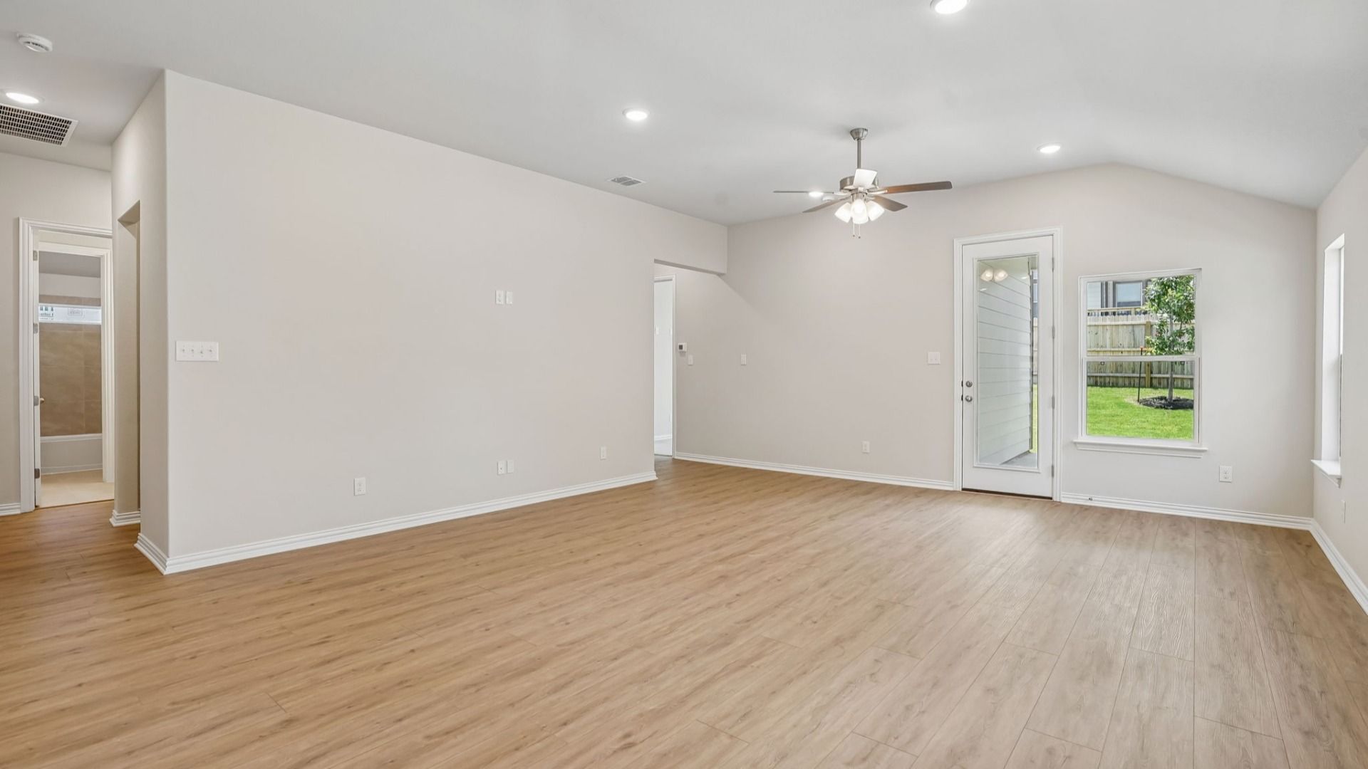 An expansive great room showcases a ceiling fan and abundant natural light, creating a bright and inviting space.