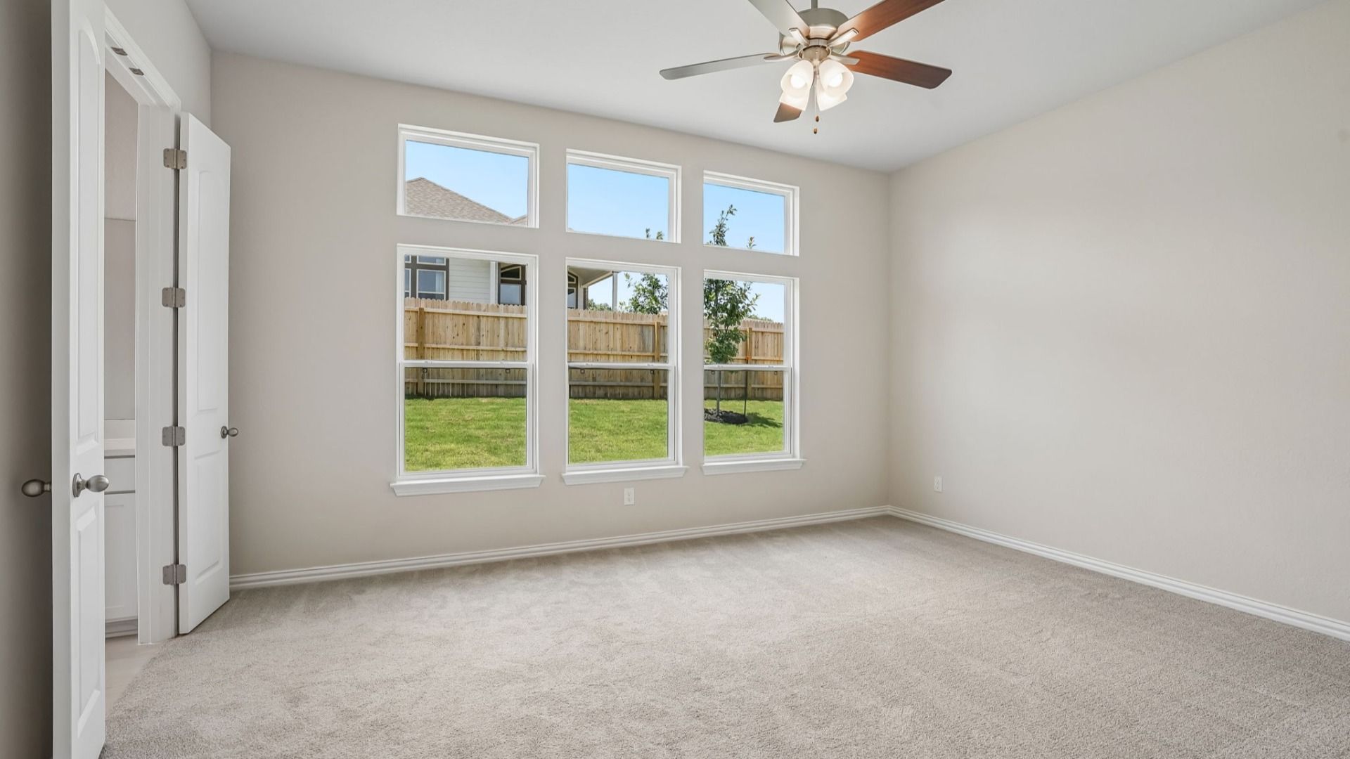 Spacious owner's suite with transom windows, a ceiling fan, and abundant natural light.