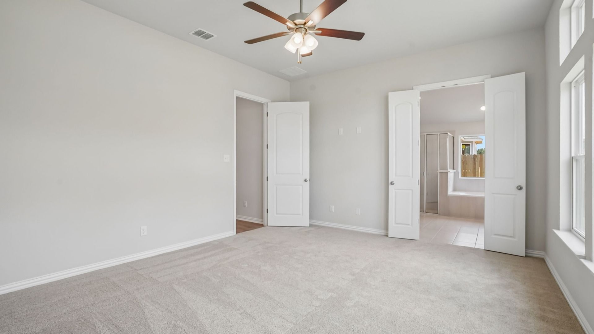 Spacious owner's suite with transom windows, a ceiling fan, and abundant natural light.