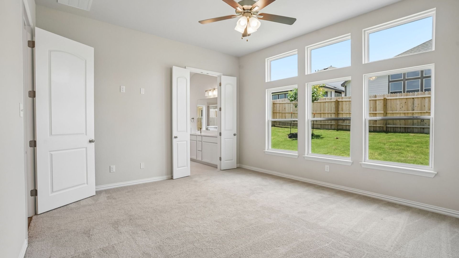 Spacious owner's suite with transom windows, a ceiling fan, and abundant natural light.