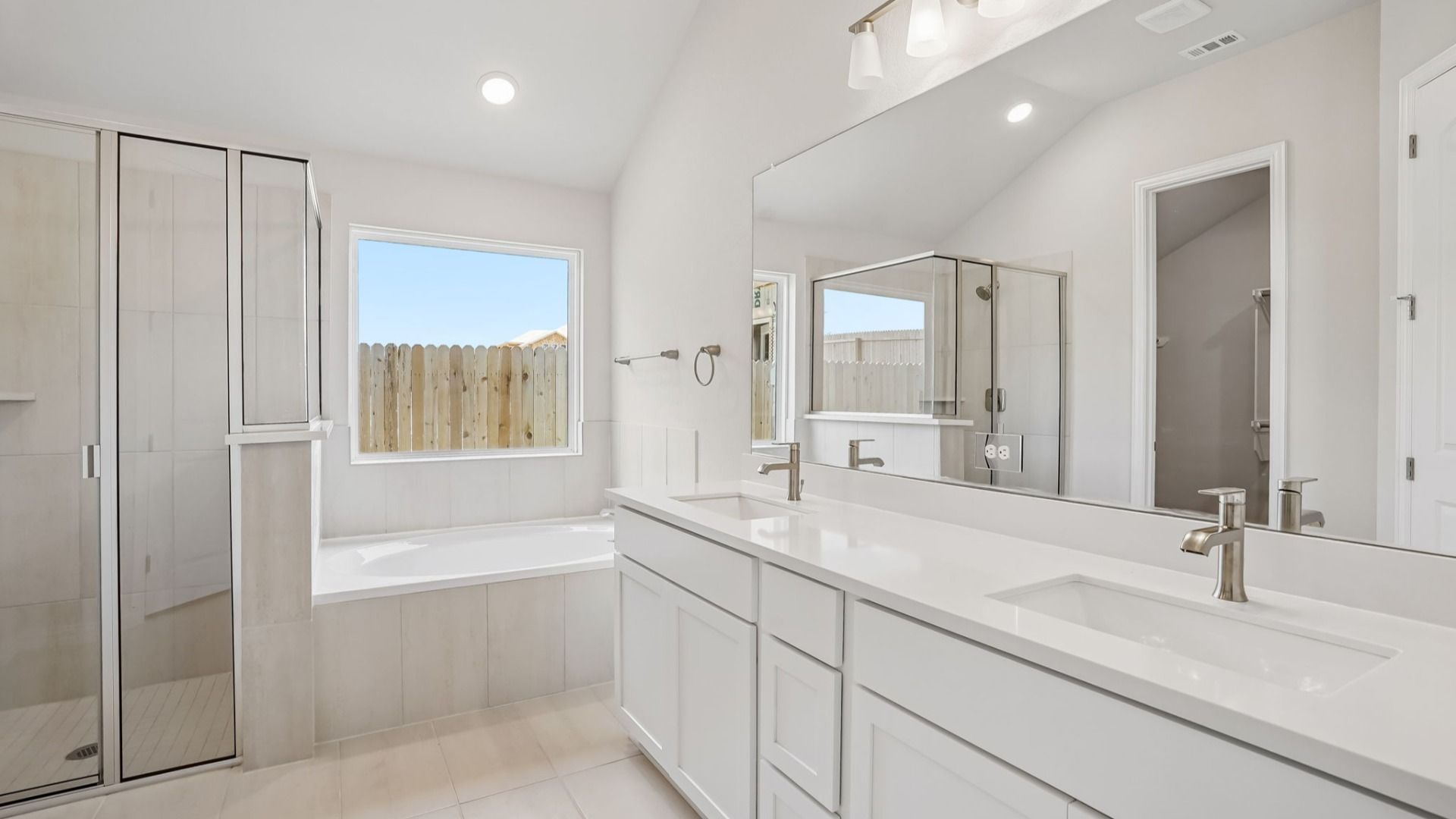 Luxurious owner's bath featuring a picture window, garden tub, glass shower & dual vanity.