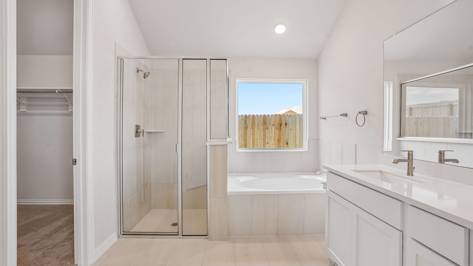 Luxurious owner's bath featuring a picture window, garden tub, glass shower & dual vanity.