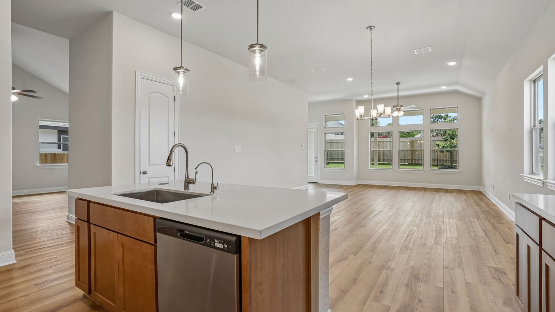 An expansive great room showcases a chandelier, transom windows, and natural light, creating a bright and inviting space.
