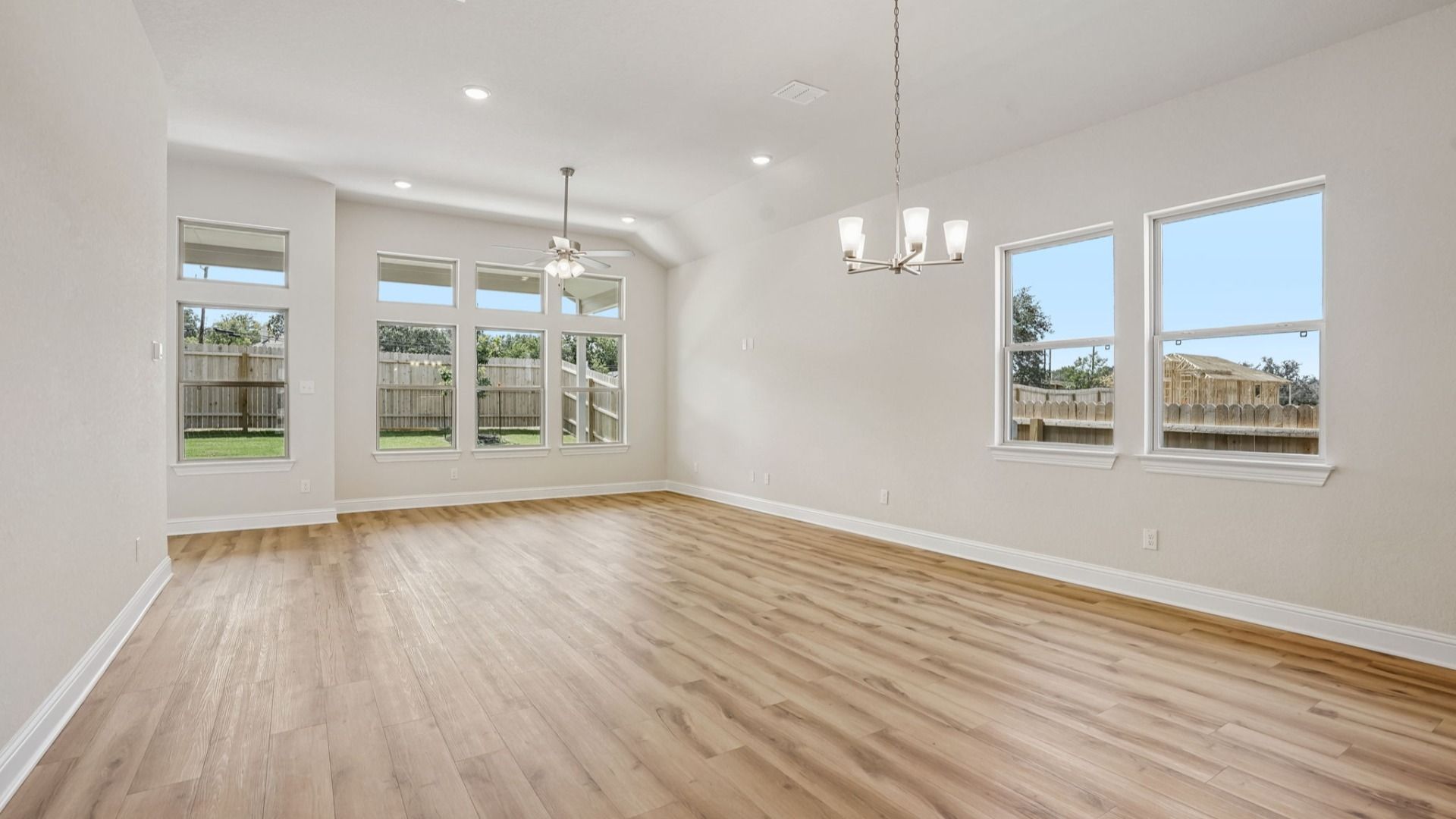 An expansive great room showcases a chandelier, transom windows, and natural light, creating a bright and inviting space.