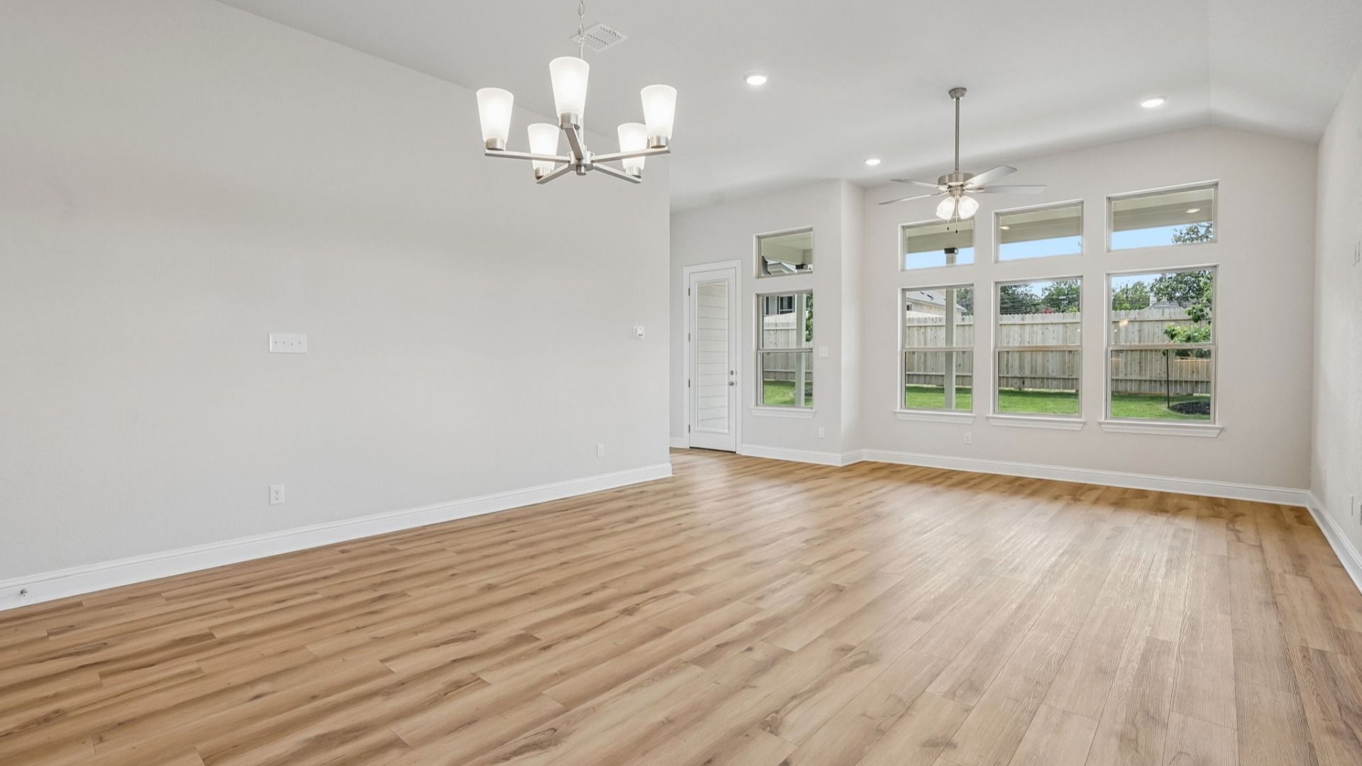 An expansive great room showcases a chandelier, transom windows, and natural light, creating a bright and inviting space.