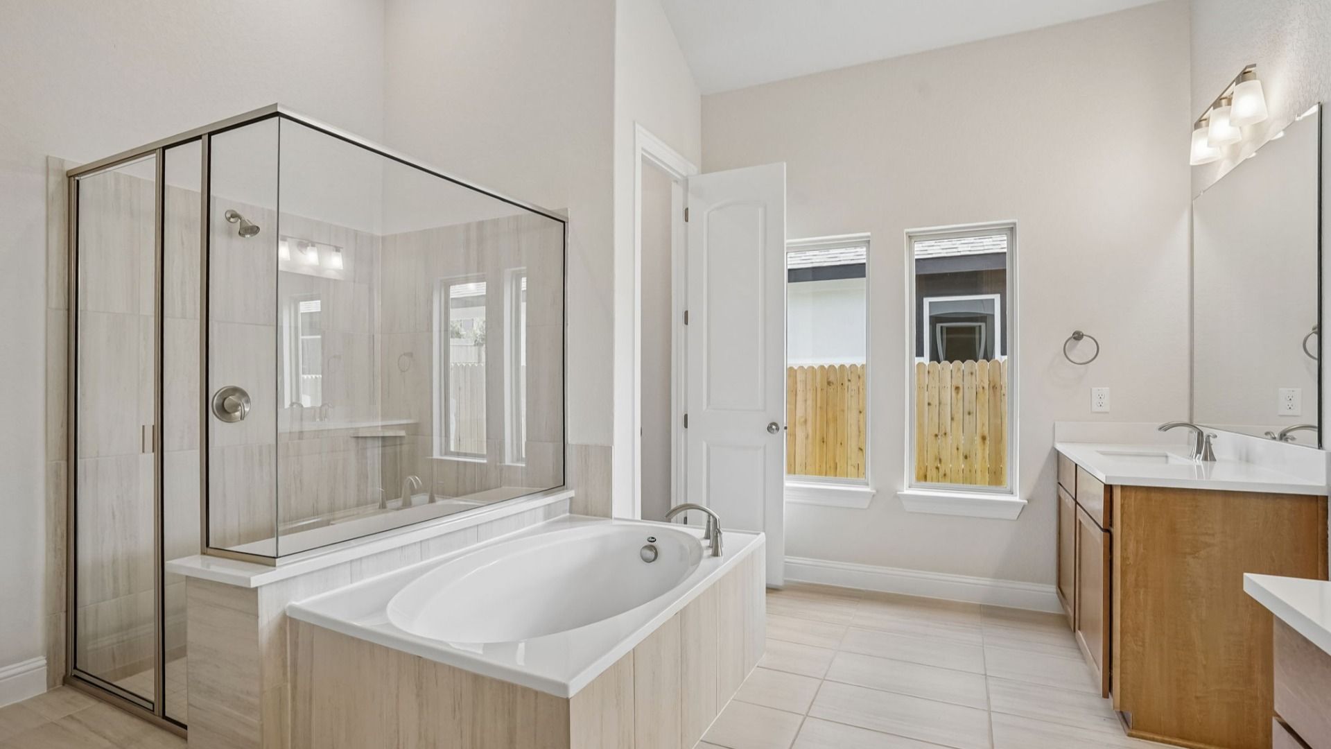 Owner's bath features a garden tub, glass-framed shower, and two separate vanities.