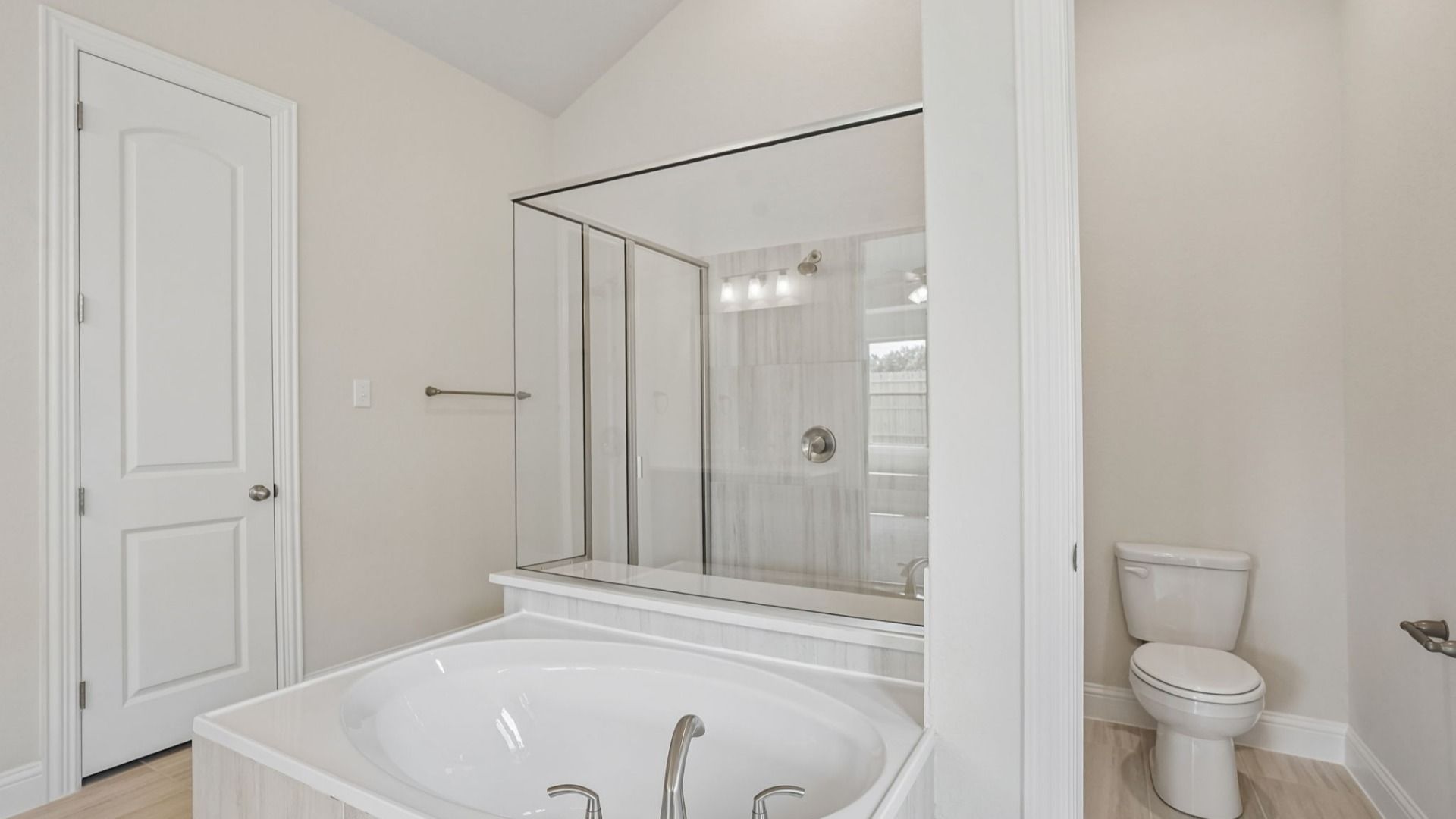 Owner's bath features a garden tub, glass-framed shower, and two separate vanities.