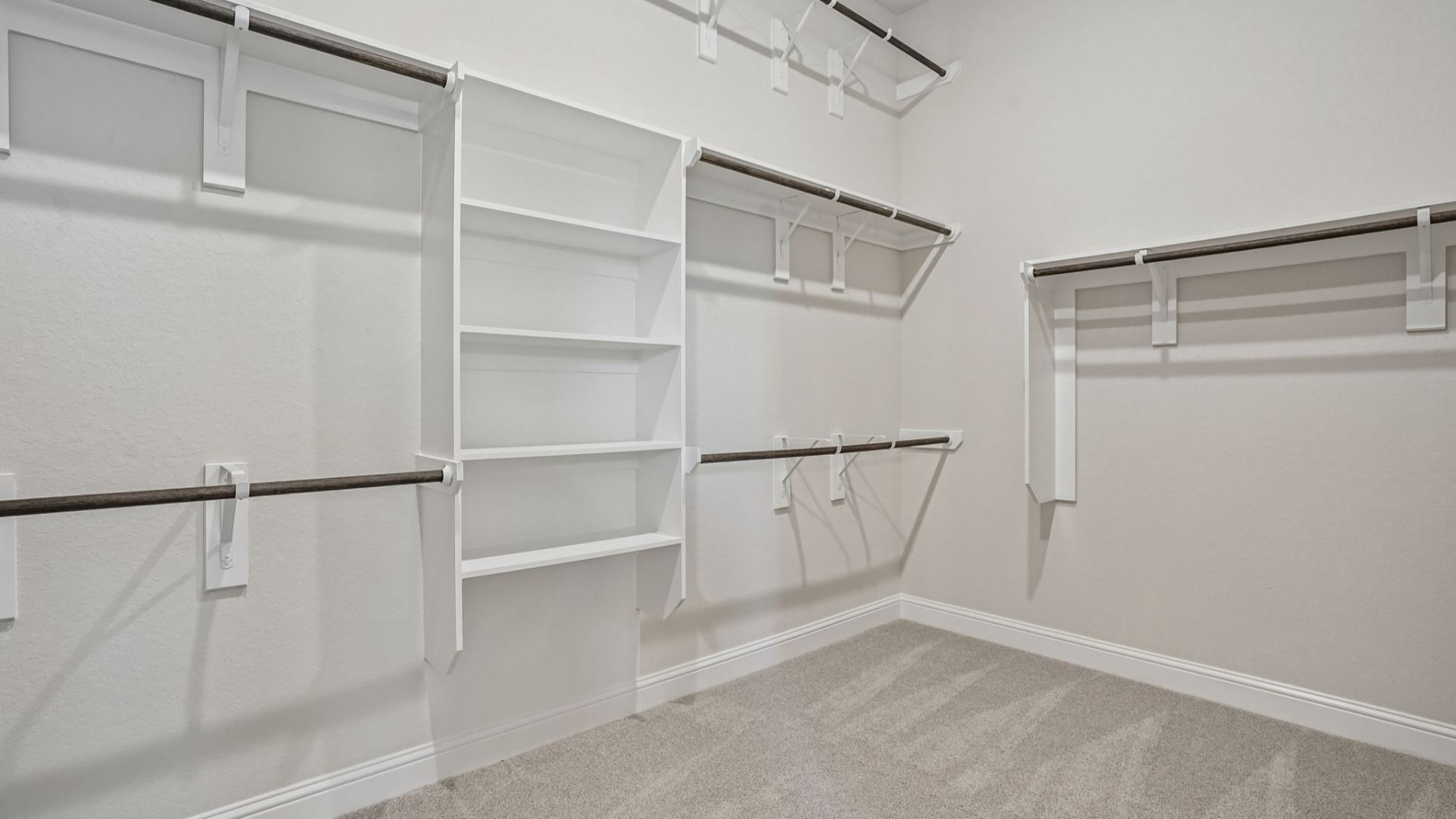Generously sized Owner's Closet featuring three rows of clothing rods and built-in shelving