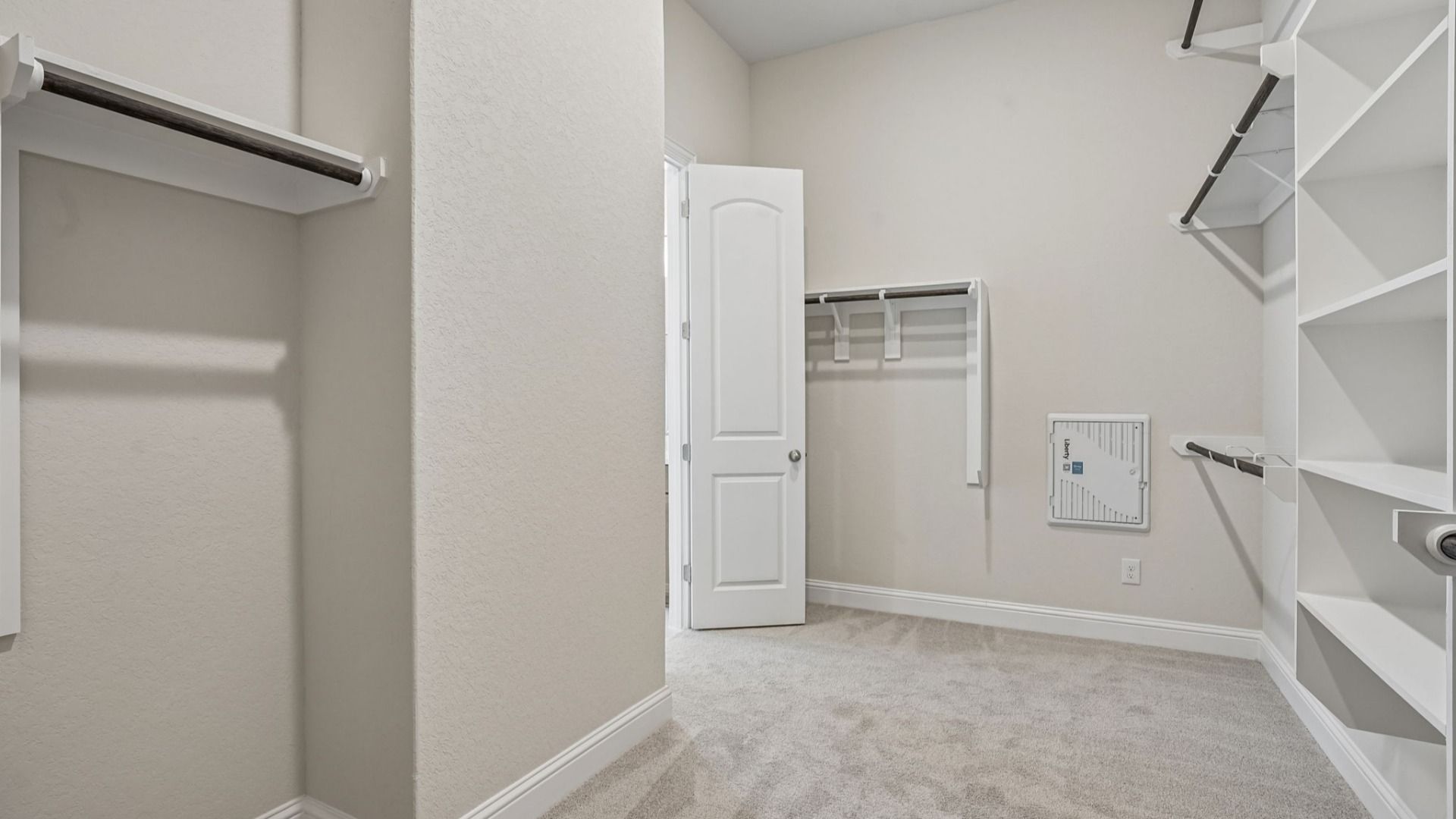 Generously sized Owner's Closet featuring three rows of clothing rods and built-in shelving