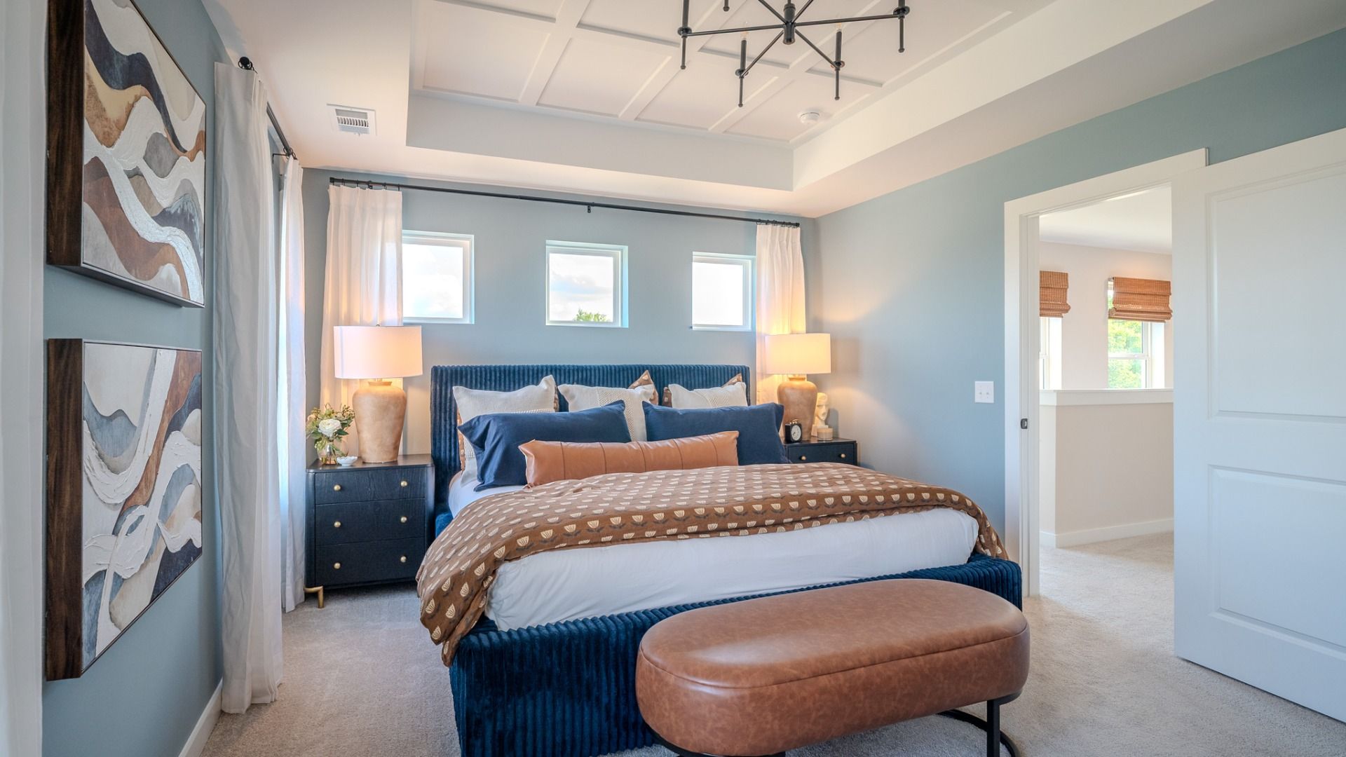Primary suite with tray and accent ceiling, carpet, and windows