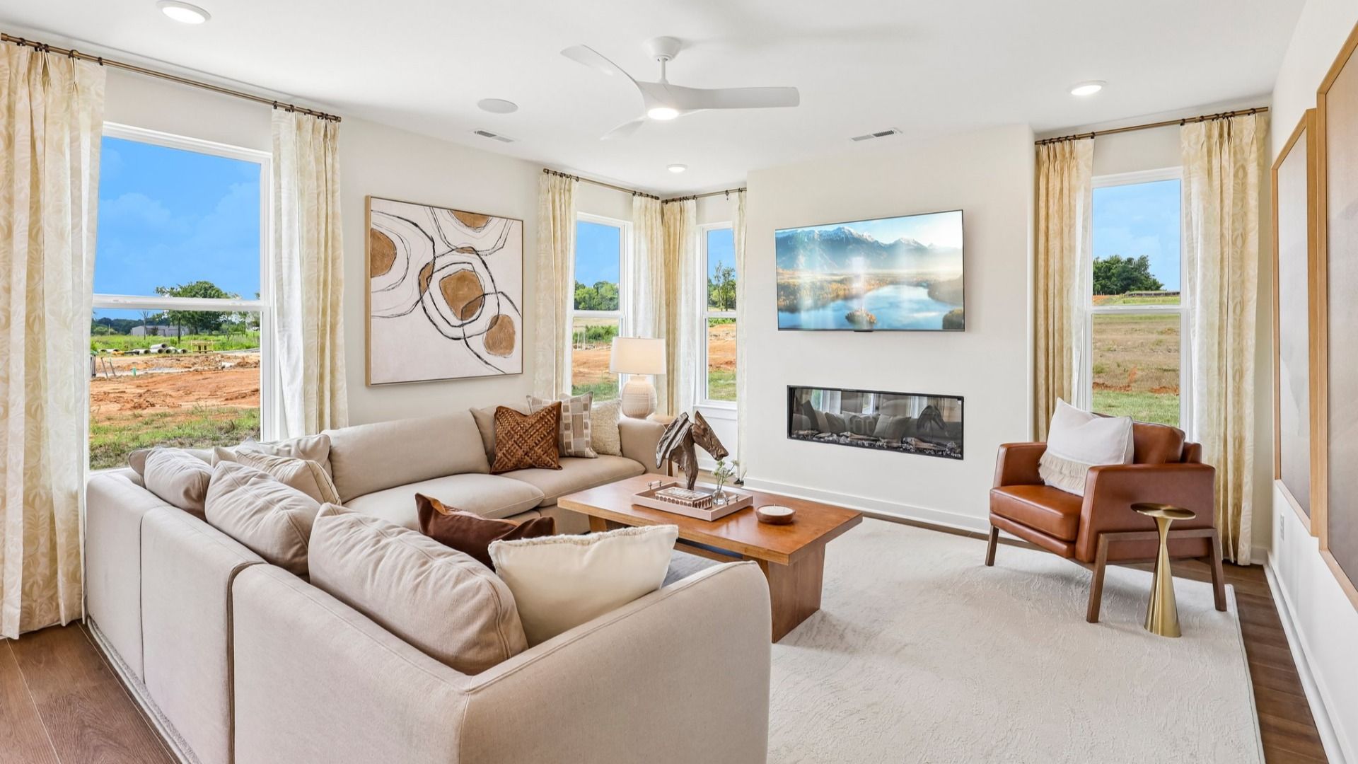 Gathering room with ceiling fan, hard surface flooring, fireplace, and natural lighting from windows