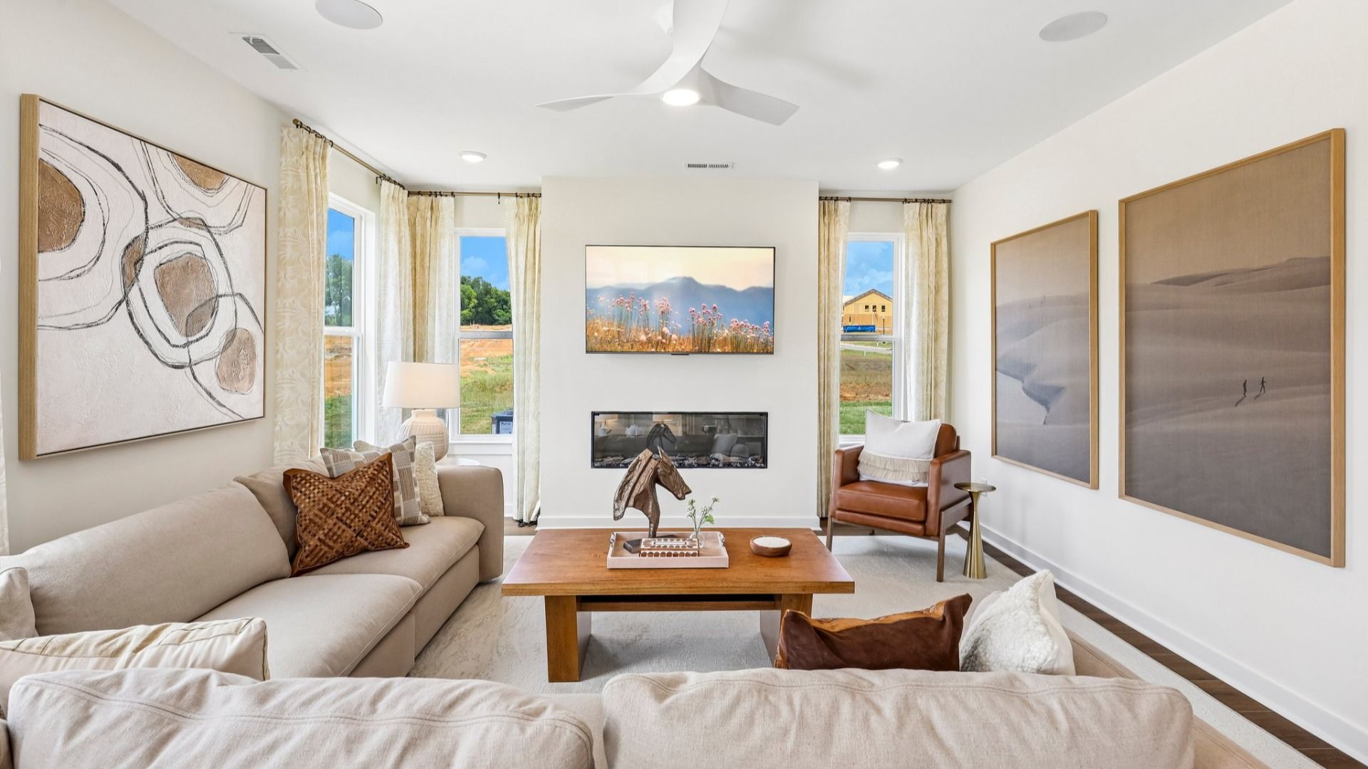 Gathering room with ceiling fan, hard surface flooring, fireplace, and natural lighting from windows