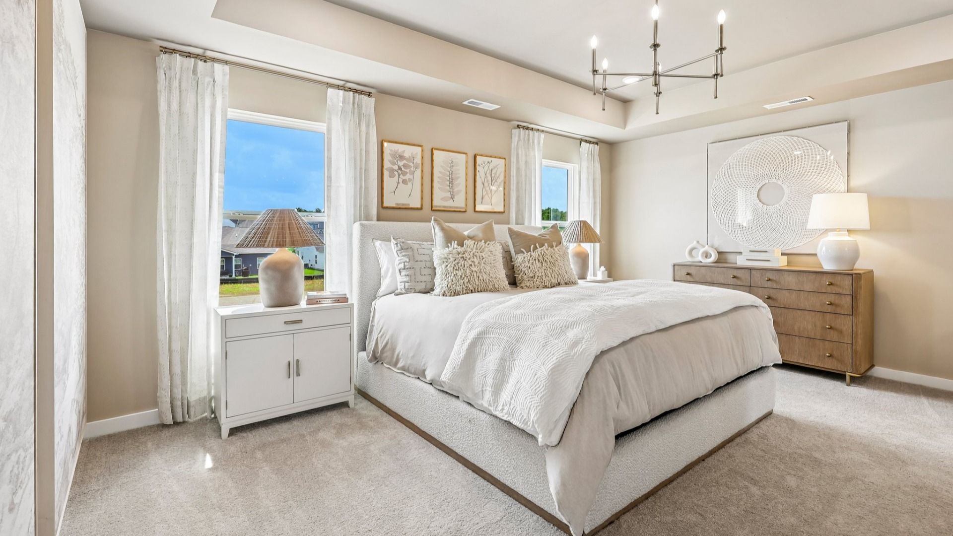 Primary suite with tray ceiling, windows, and carpet