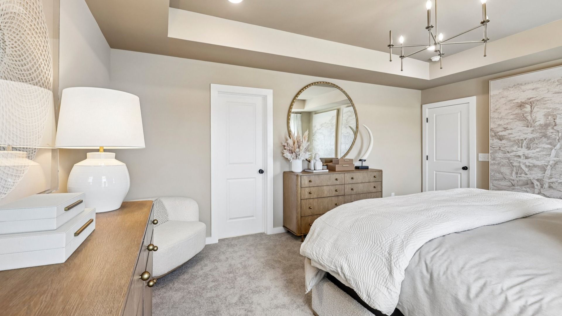 Primary suite with tray ceiling, windows, and carpet