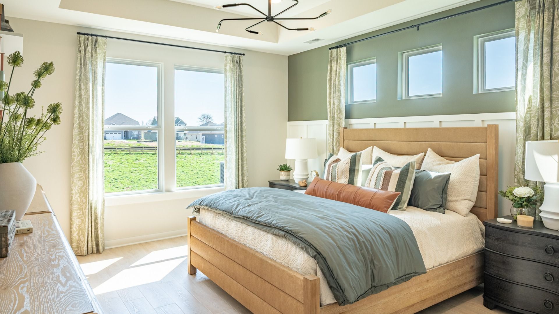 Primary suite with bright natural lighting form windows, hard surface flooring, and tray ceiling