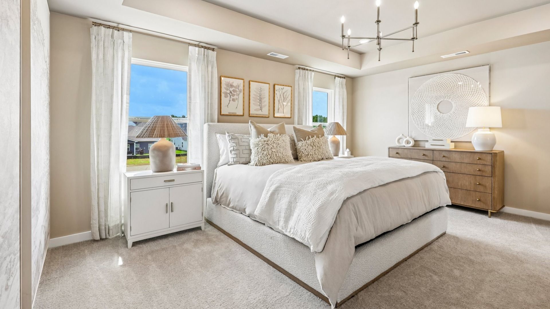 Primary suite with tray ceiling, windows, and carpet