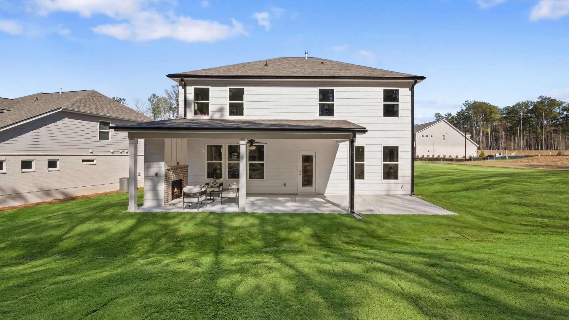 Rear exterior of home with covered patio, ceiling fan, and fireplace