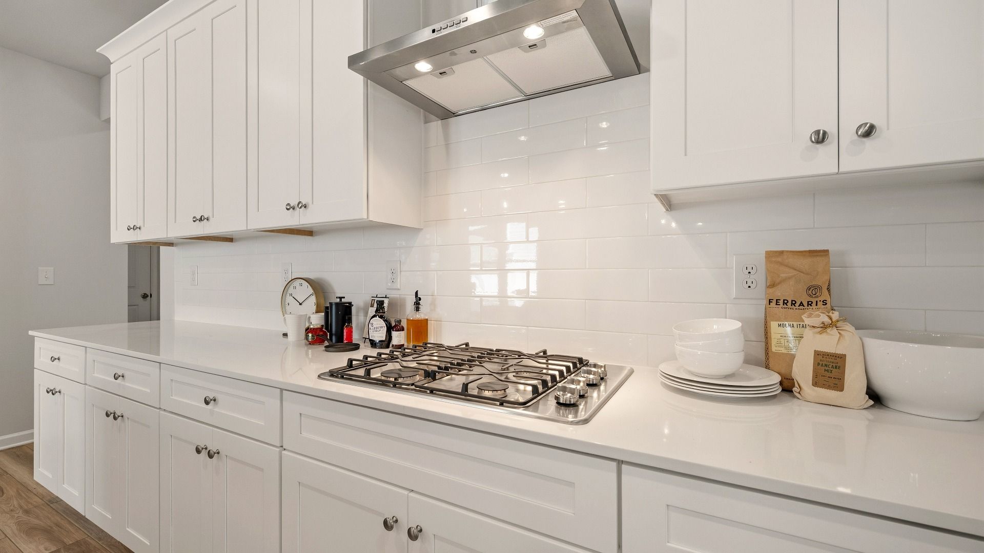 Kitchen with tile backsplash, quartz countertops, and white cabinetry