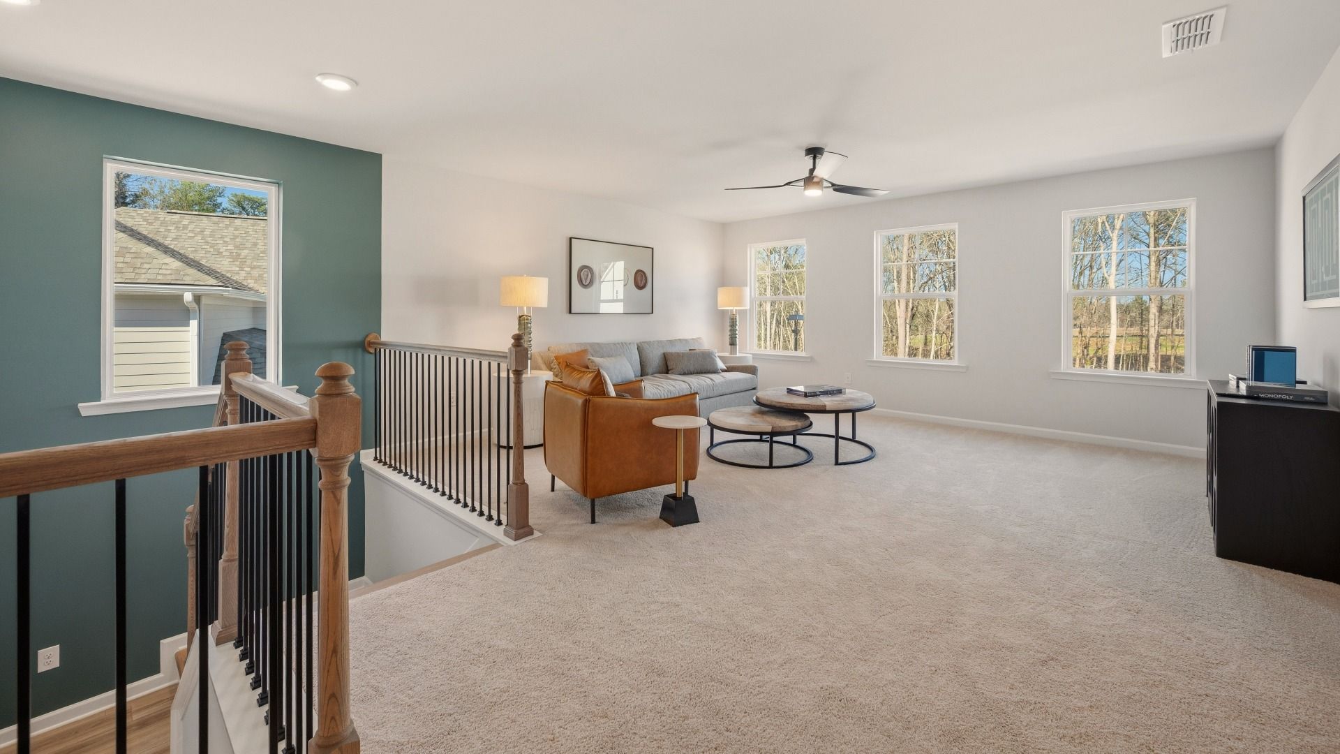Spacious loft area with ceiling fan and carpet