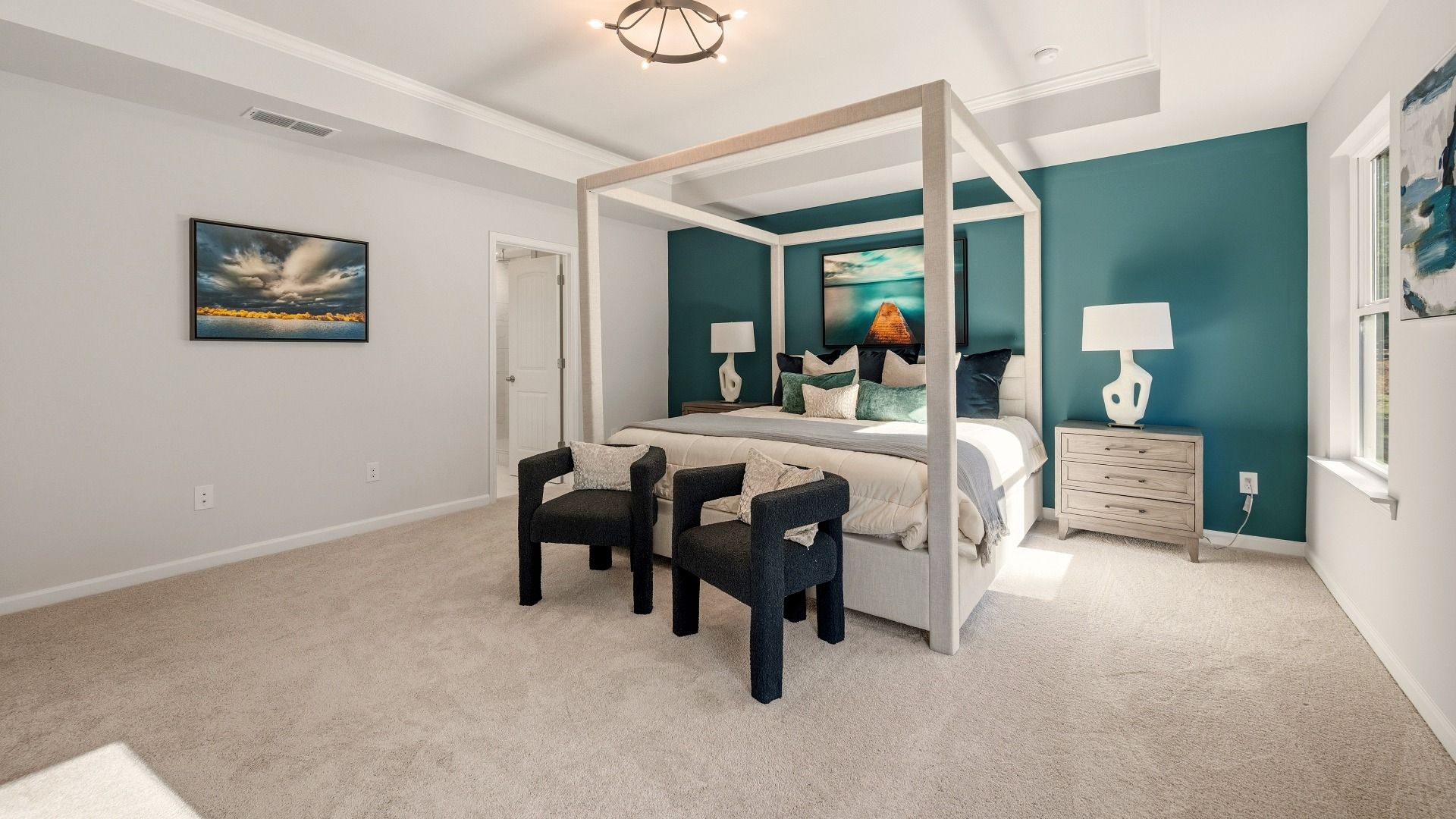 Primary suite with tray ceiling, carpet, and bright natural lighting from windows