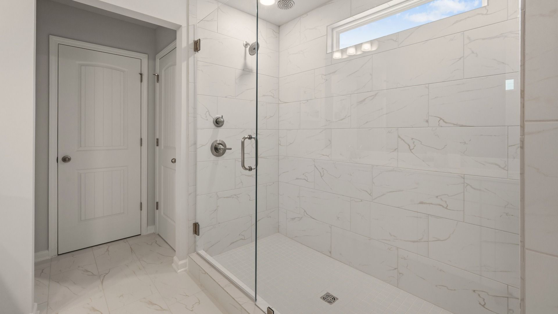 Primary bathroom with glass enclosed shower with shower window