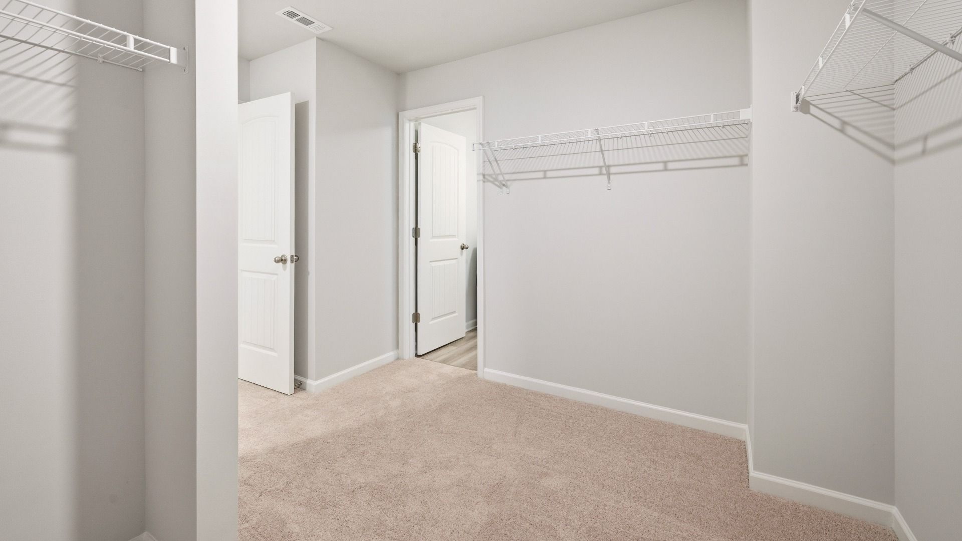Primary closet with carpet and ventilated shelves