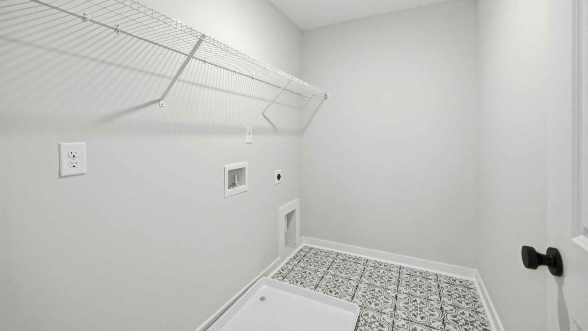 Dedicated laundry space with accent tile flooring and ventilated shelf
