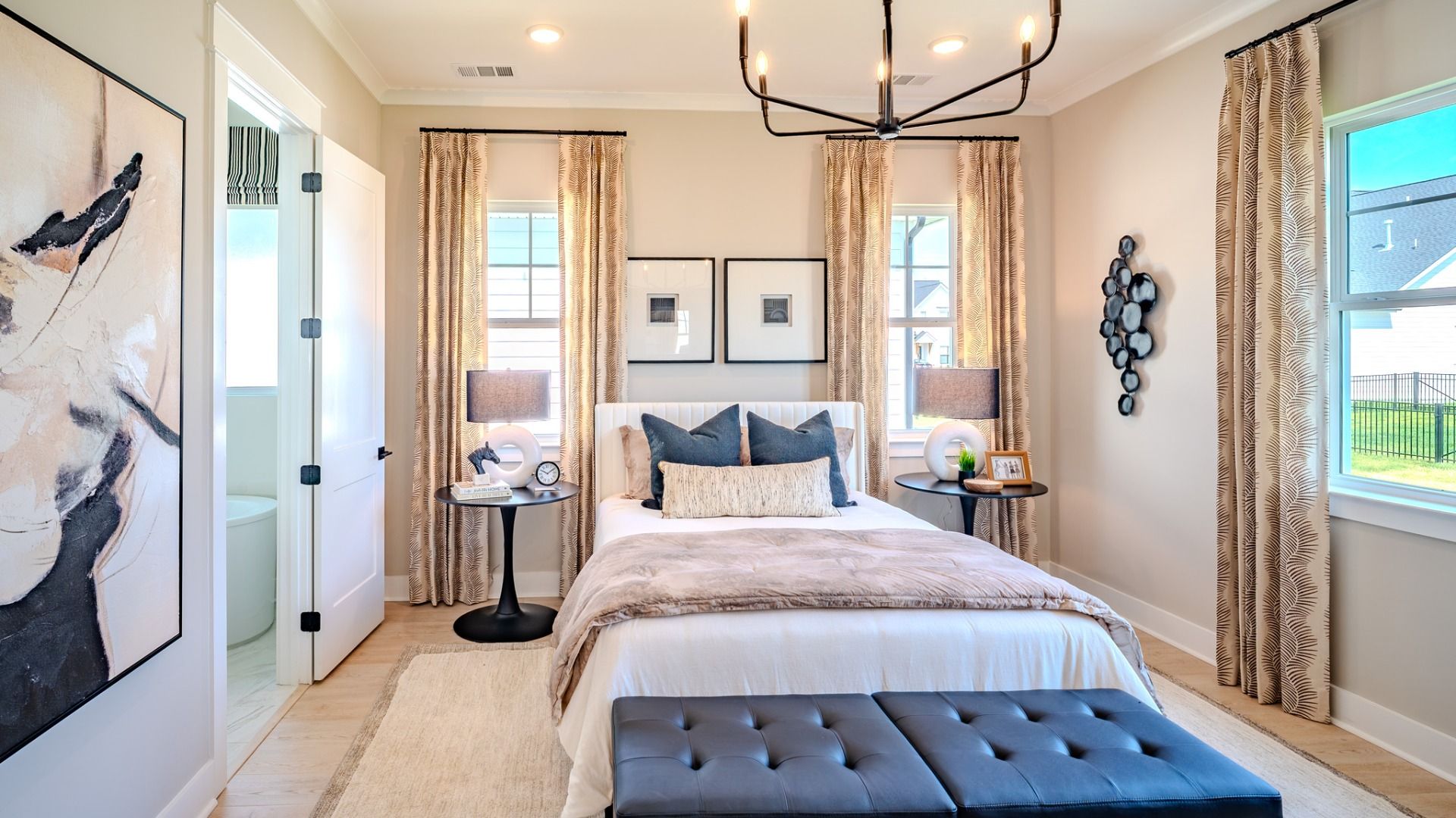 Spacious primary suite with tray ceiling, hard surface flooring, and access to primary bathroom