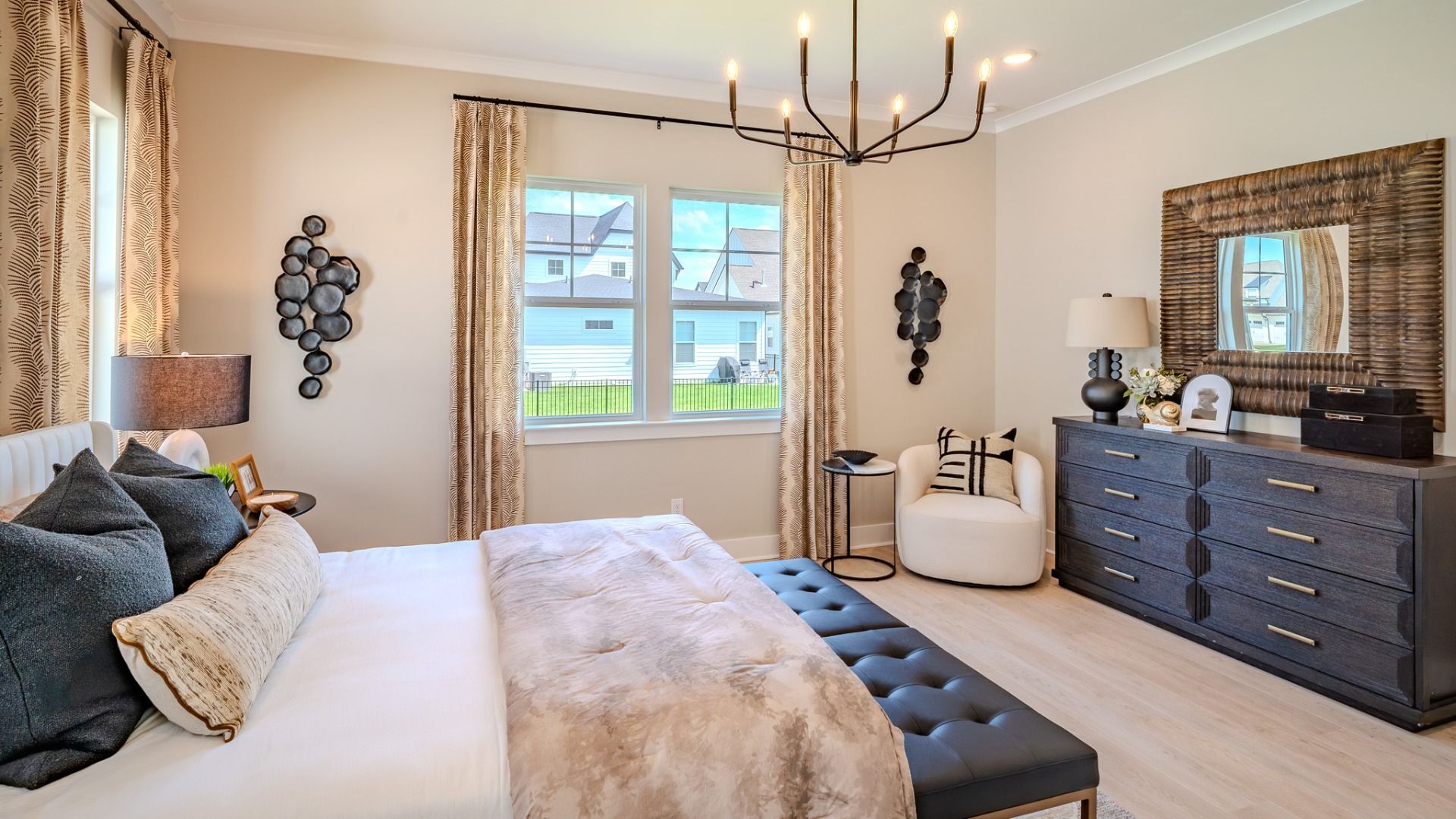 Spacious primary suite with tray ceiling, hard surface flooring, and windows