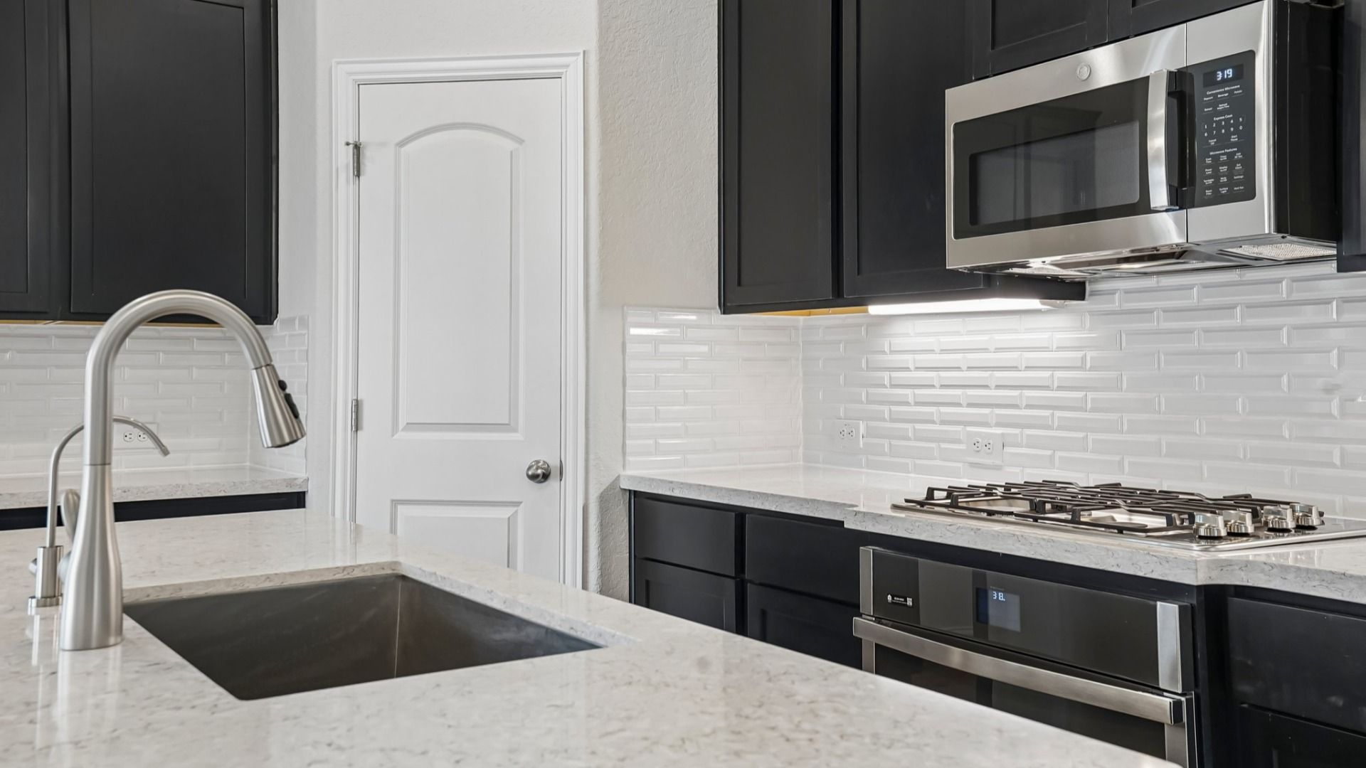 Espresso cabinets, sleek countertops, pendant lighting, center island, and gas cooking create a stylish kitchen.
