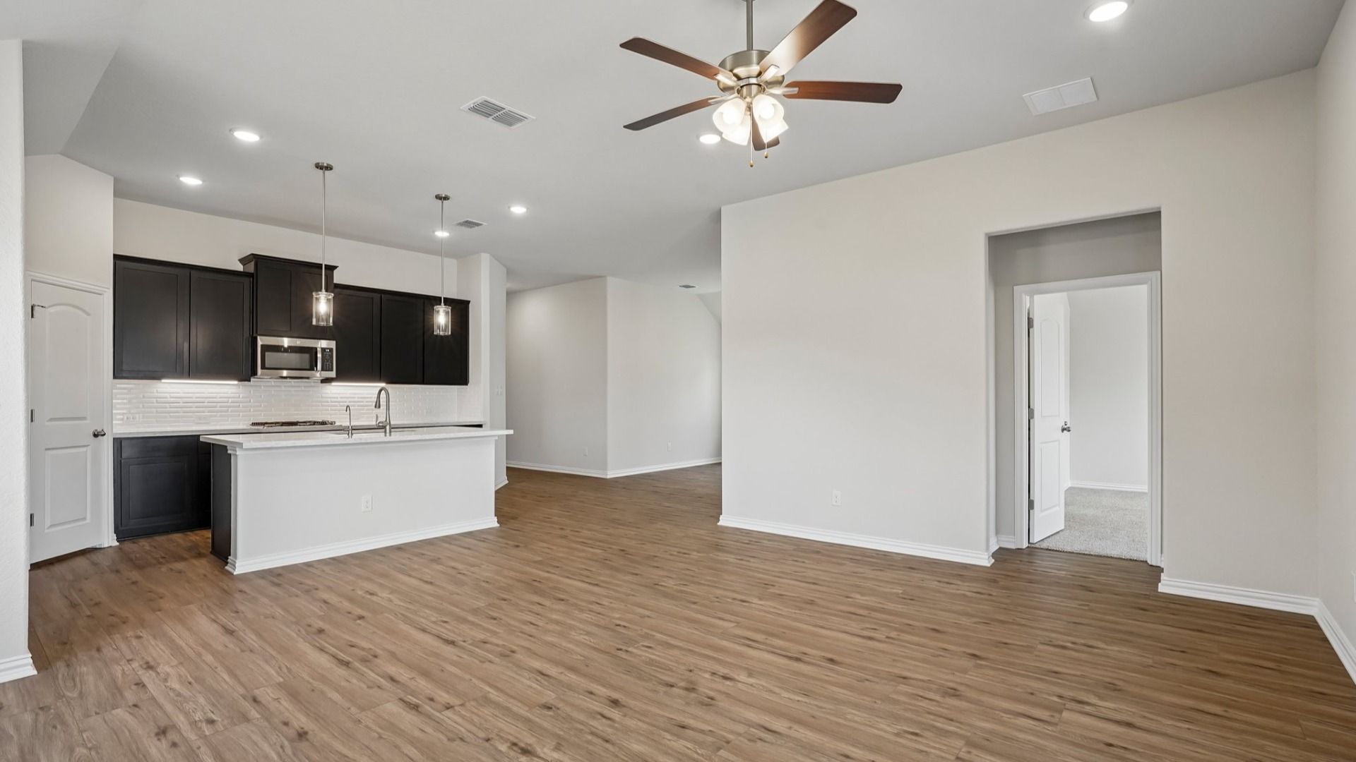 Espresso cabinets, white countertops, pendant lighting, center island, and gas cooking create a stylish kitchen.