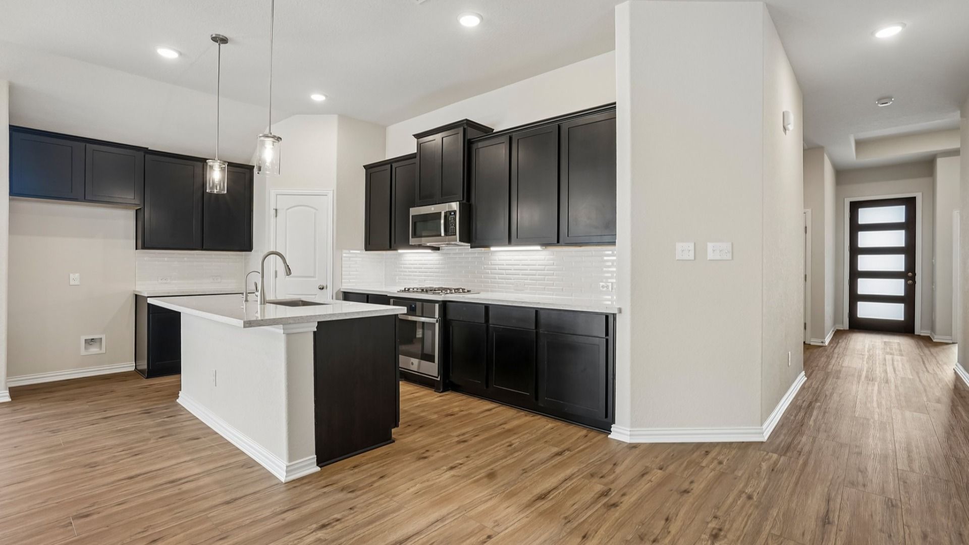 Espresso cabinets, sleek countertops, pendant lighting, center island, and gas cooking create a stylish kitchen.