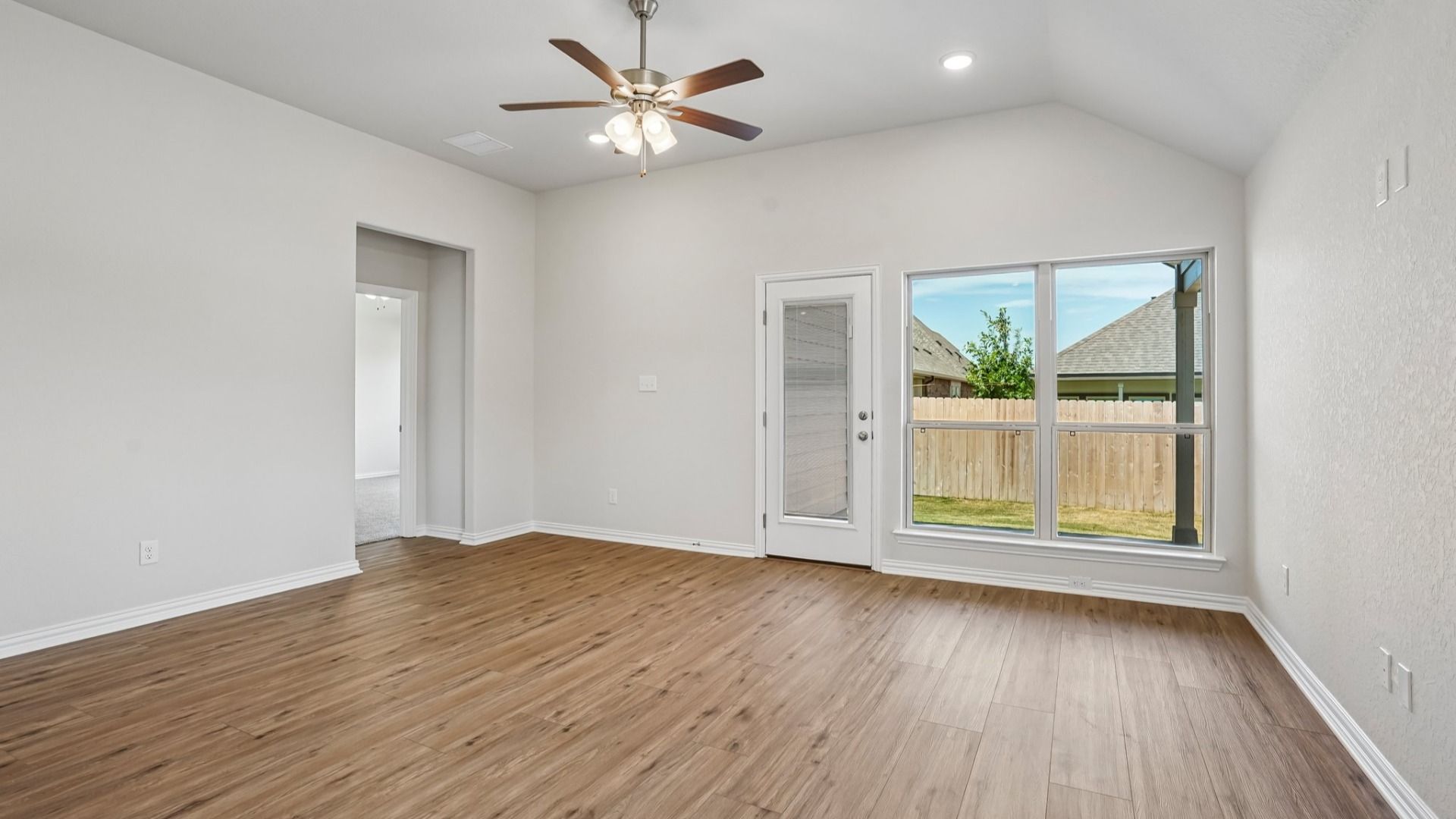 Great room opens to kitchen and dining, features a ceiling fan, and scenic backyard views for a bright, open living space.