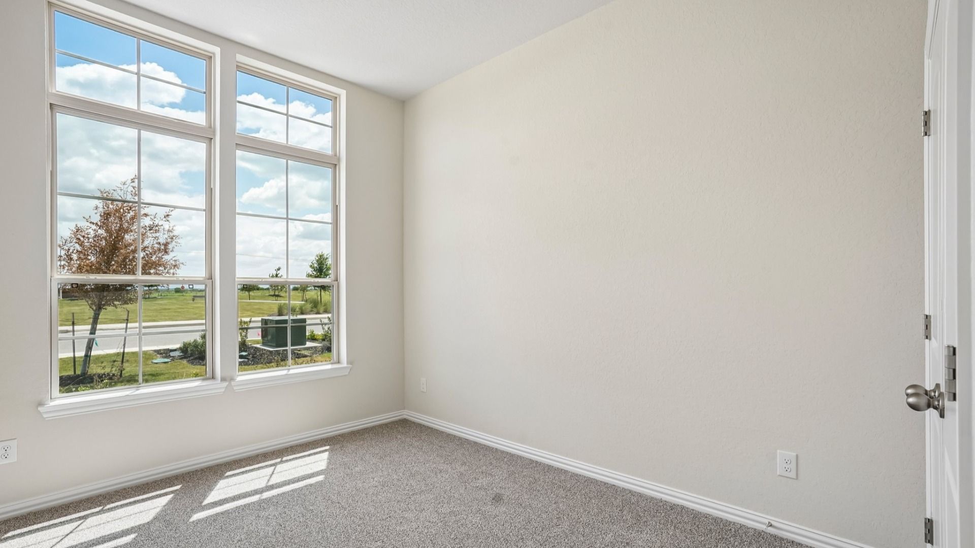 Front bedroom with transom windows and peaceful views of the green space in front of the home.