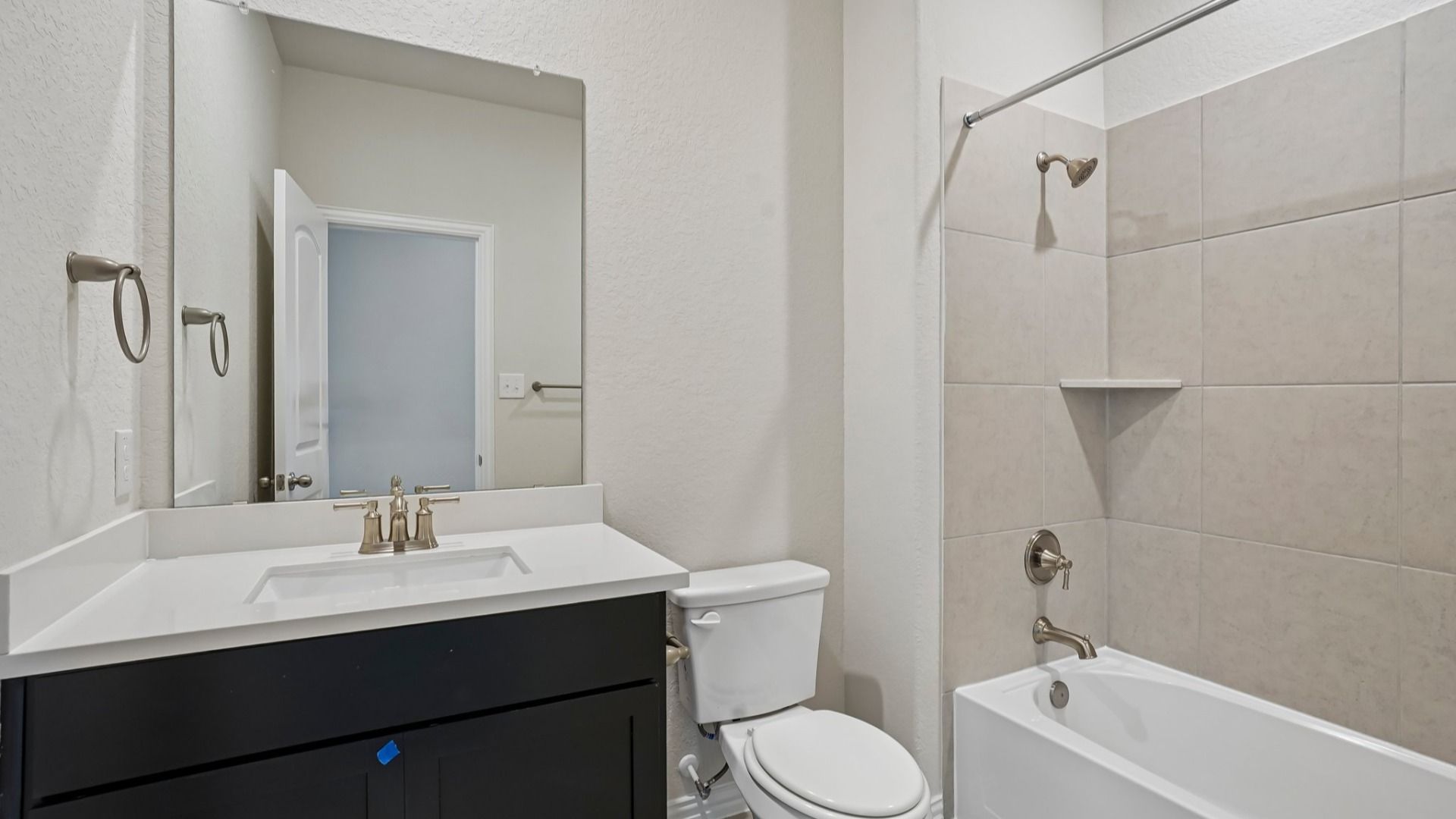 Secondary bath with ceramic tile tub/shower combo, espresso vanity, and white countertop.
