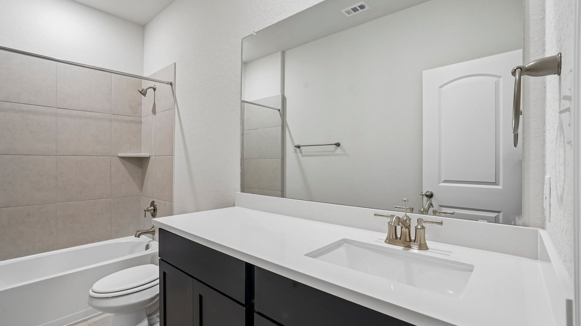 Secondary bath with ceramic tile tub/shower combo, espresso vanity, and white countertop.