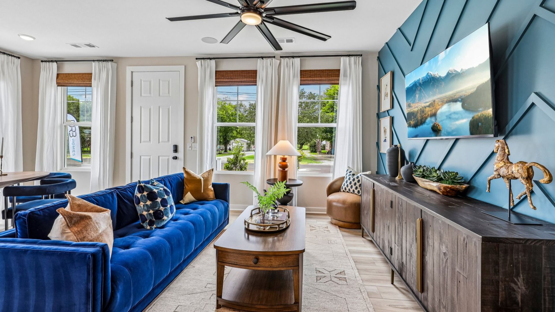 Gathering room with ceiling fan, hard surface flooring, and accent wall