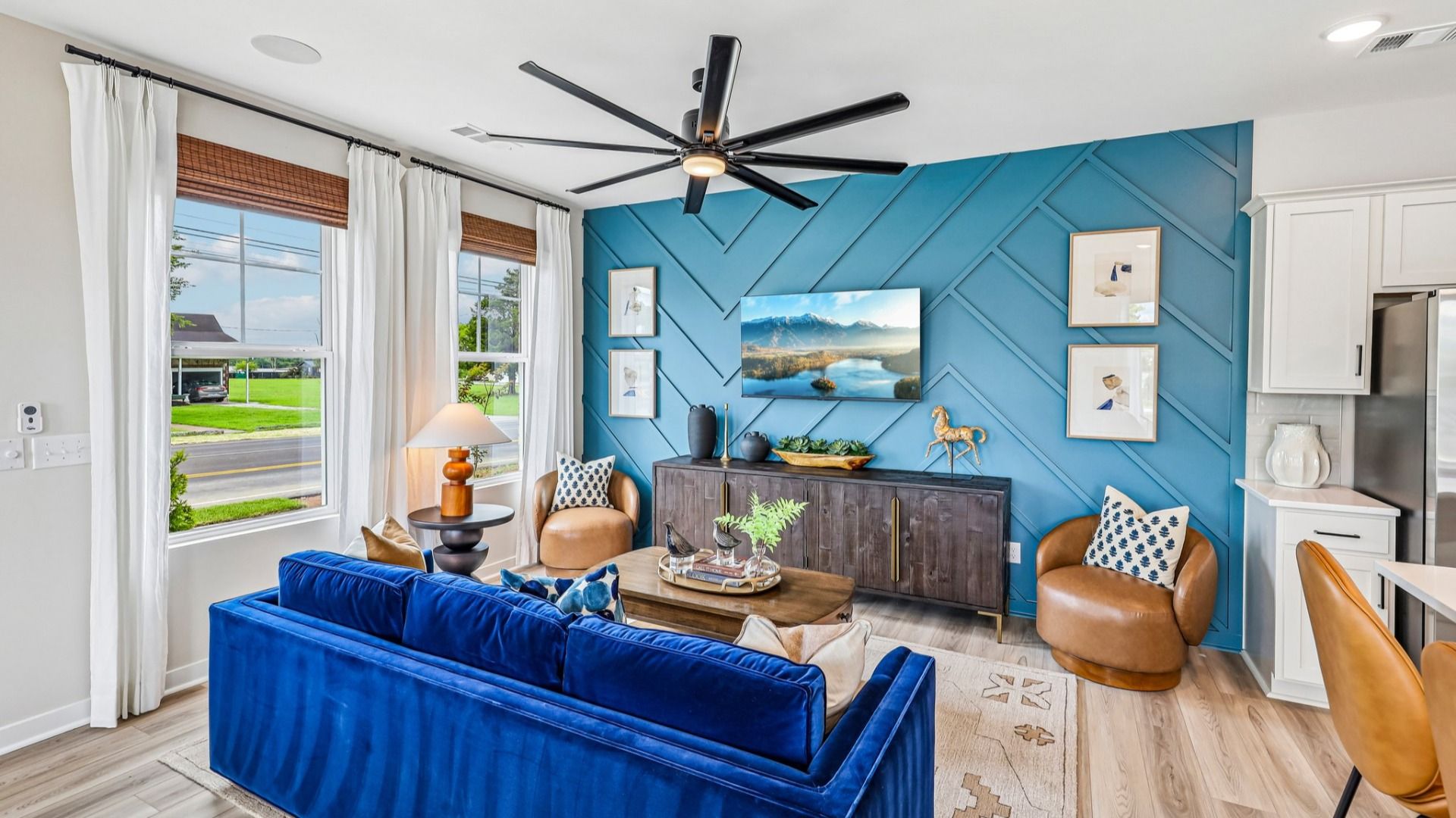 Gathering room with ceiling fan, hard surface flooring, and accent wall