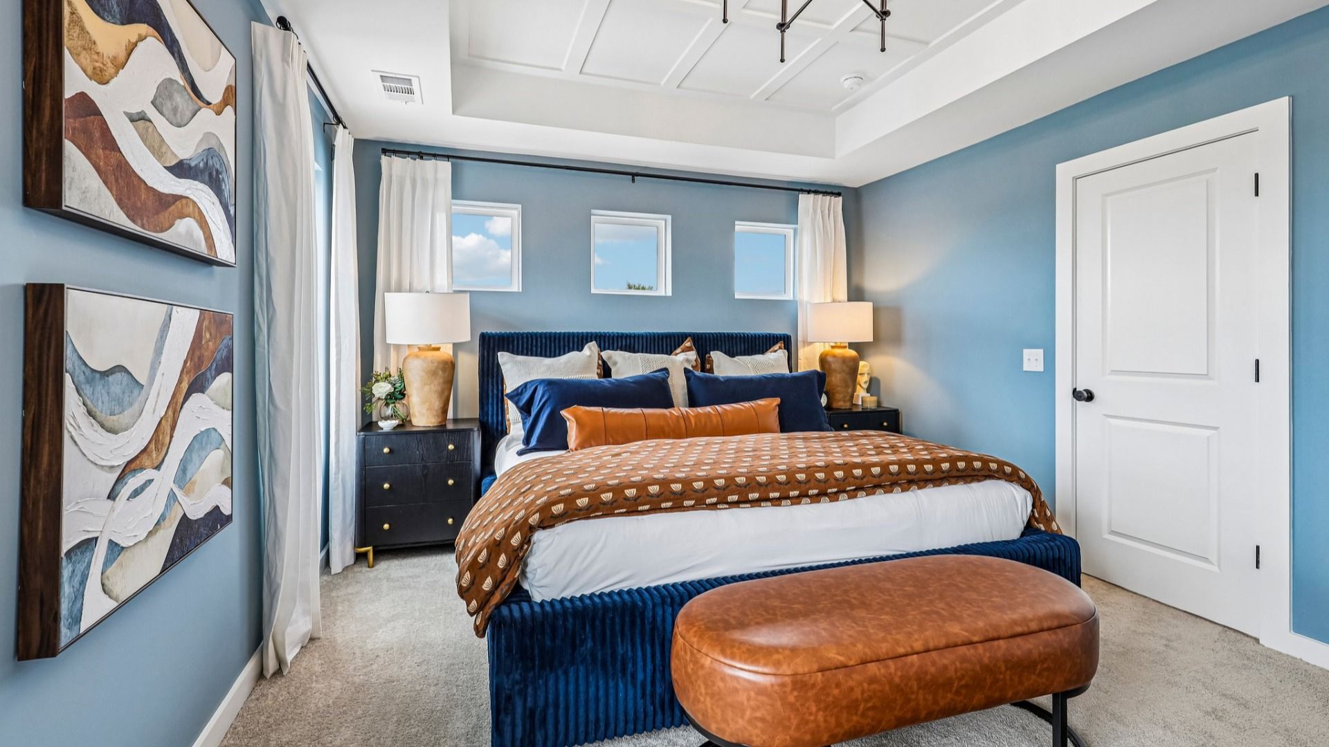 Primary suite with tray ceiling, windows, and carpet