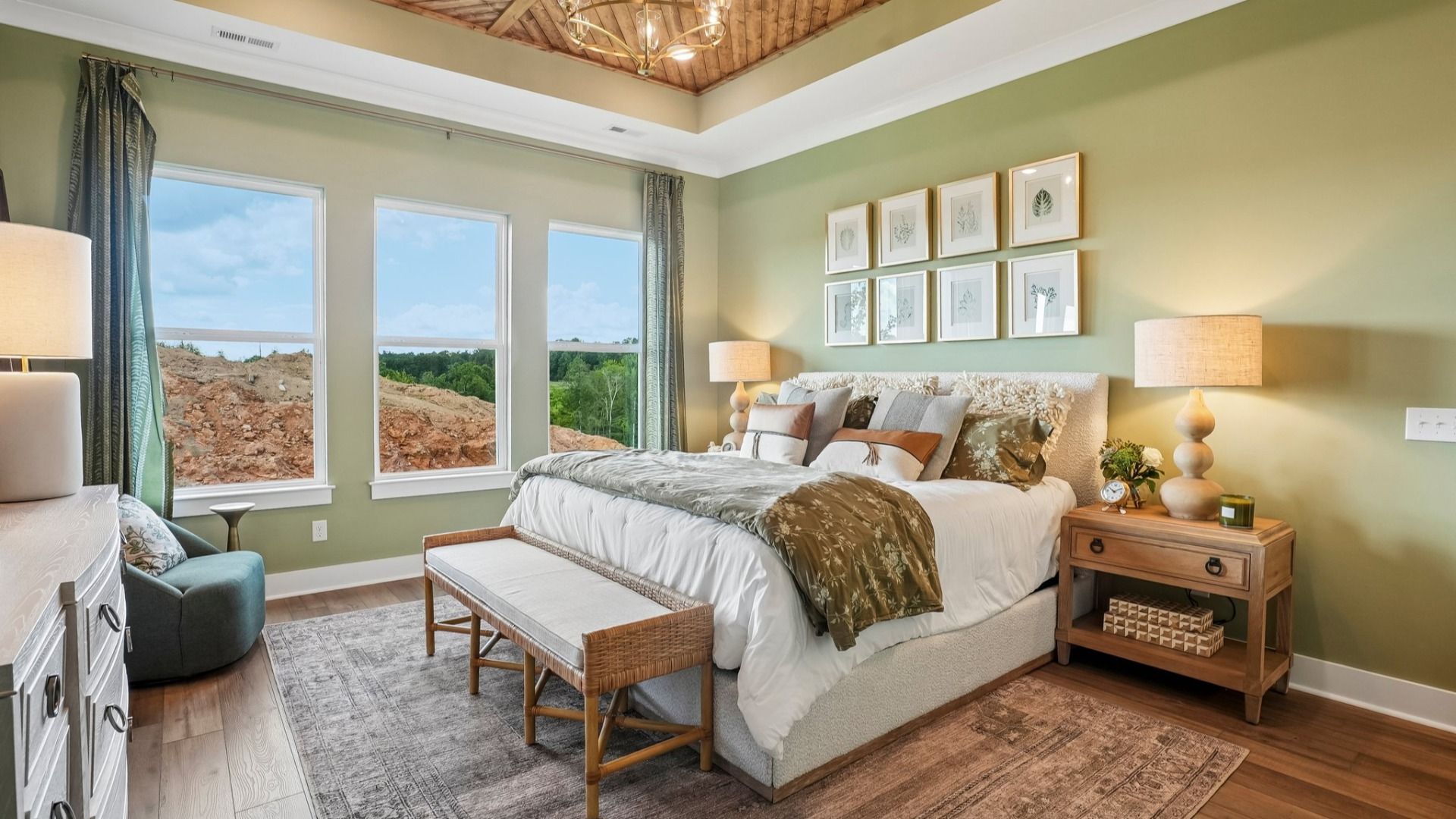 Primary suite with tray ceiling, hard surface flooring, and windows