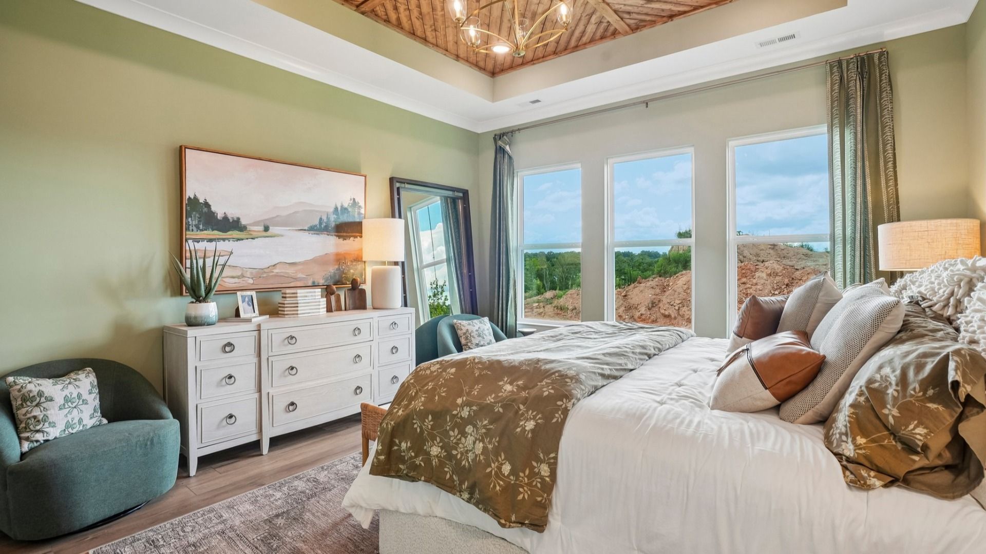 Primary suite with tray ceiling, windows, and hard surface flooring