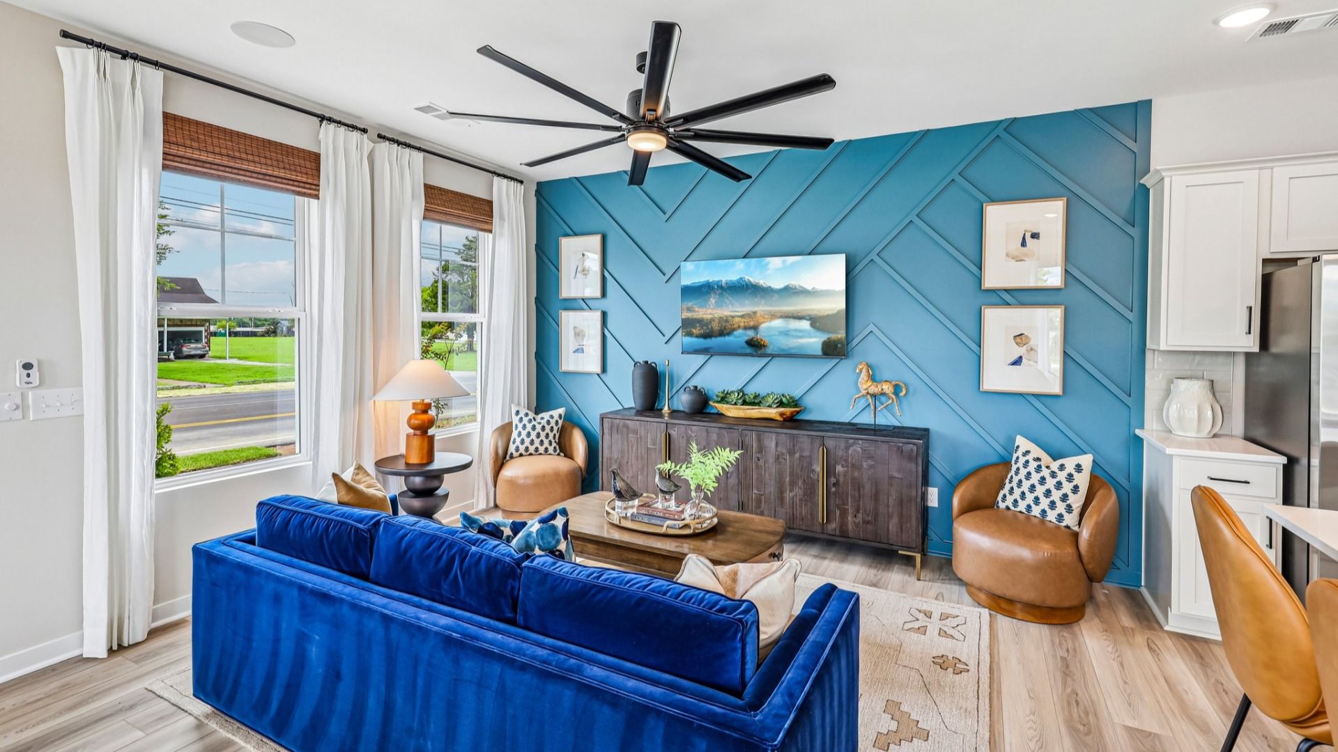 Gathering room with ceiling fan, hard surface flooring, and accent wall